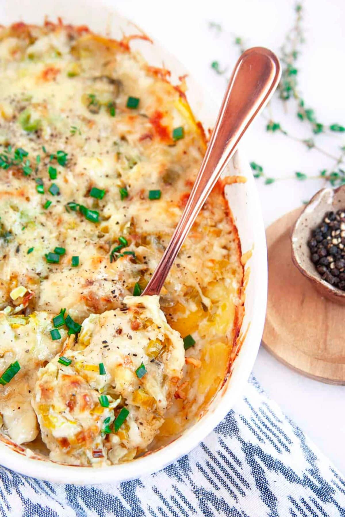 Spoonful of potato leek gratin being removed from a baking dish.