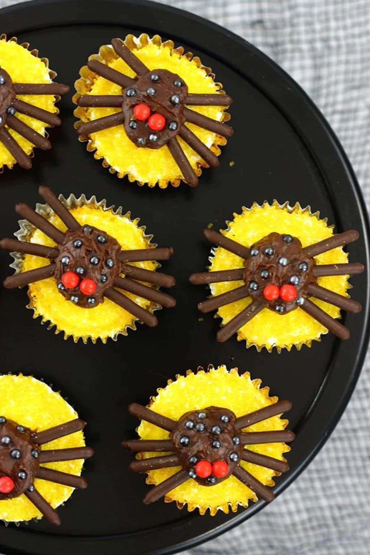 7 Halloween spider cupcakes on a black serving tray.