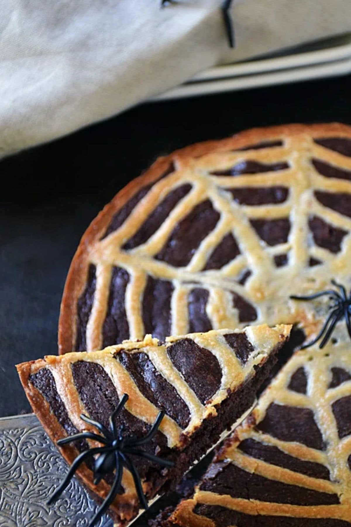 A slice of Spiderweb brownies being removed the round brownie pan.