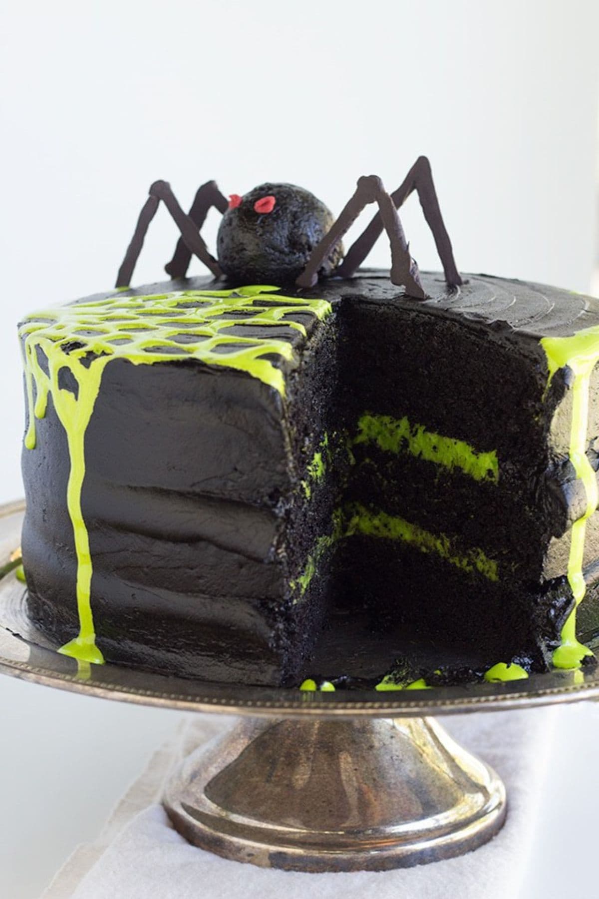 Spiderweb cake on a cake stand with a slice removed.