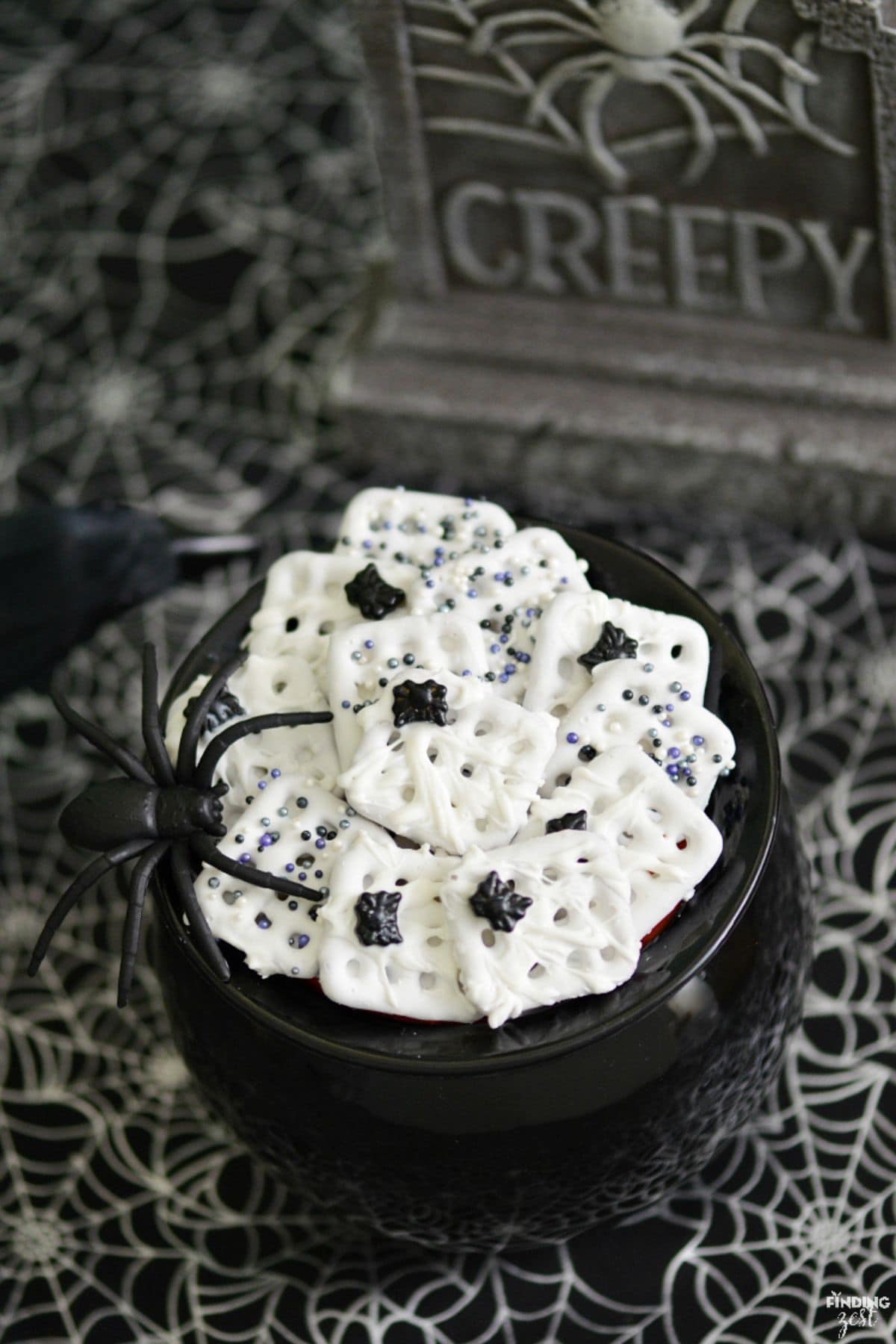 Cauldron full of white chocolate pretzels with mini spiders on the top of them.