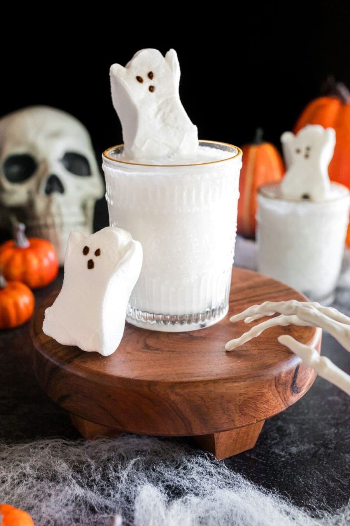 Spooky cocktail on a cake stand and topped with a ghost marshmallow peep.