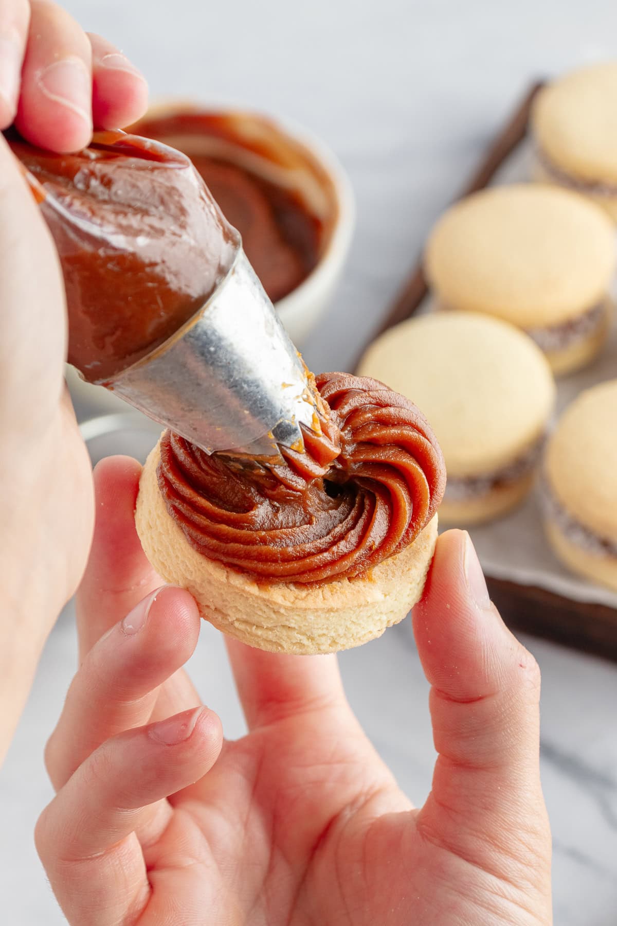 Filling a cookie with dulce de leche. 