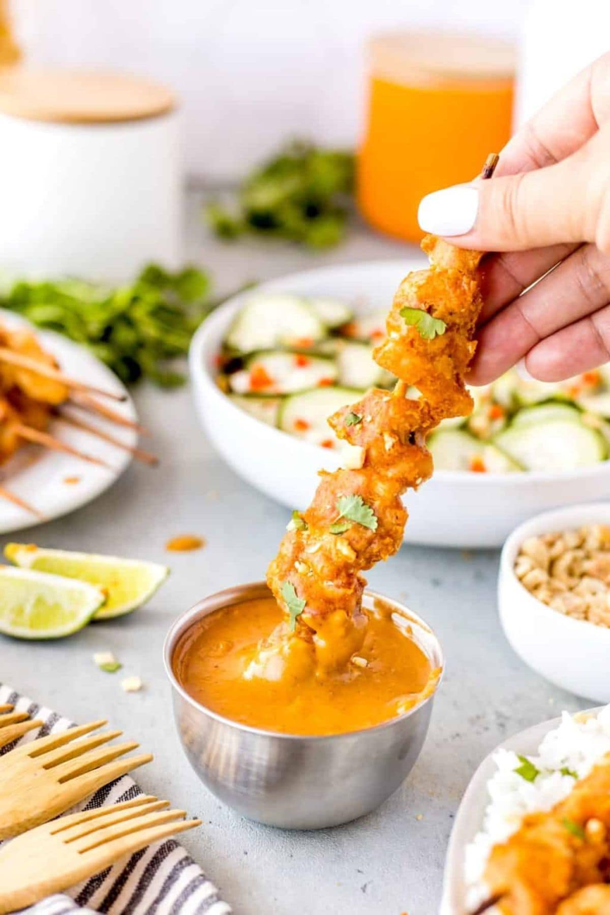 Chicken satay skewer in a womans hand.