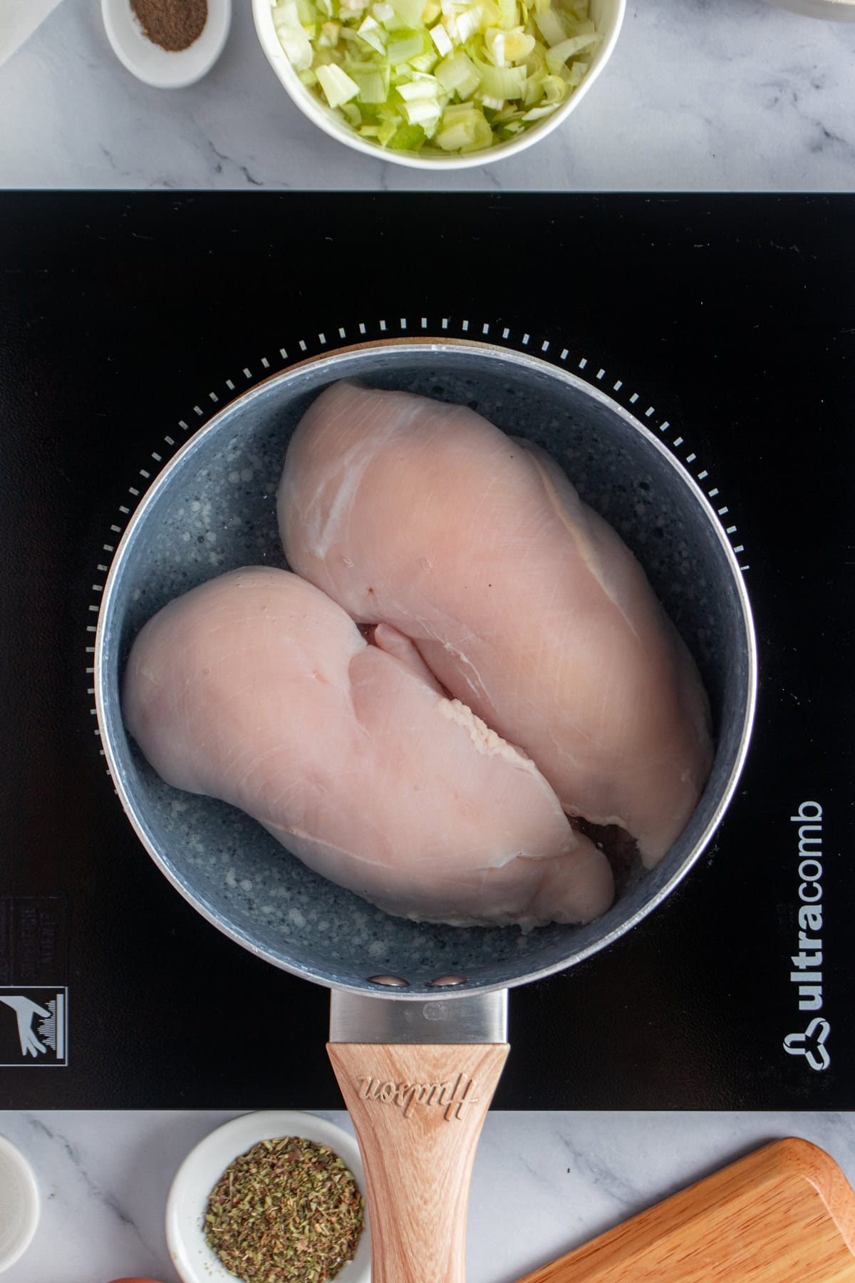 Raw chicken breast in a pot.