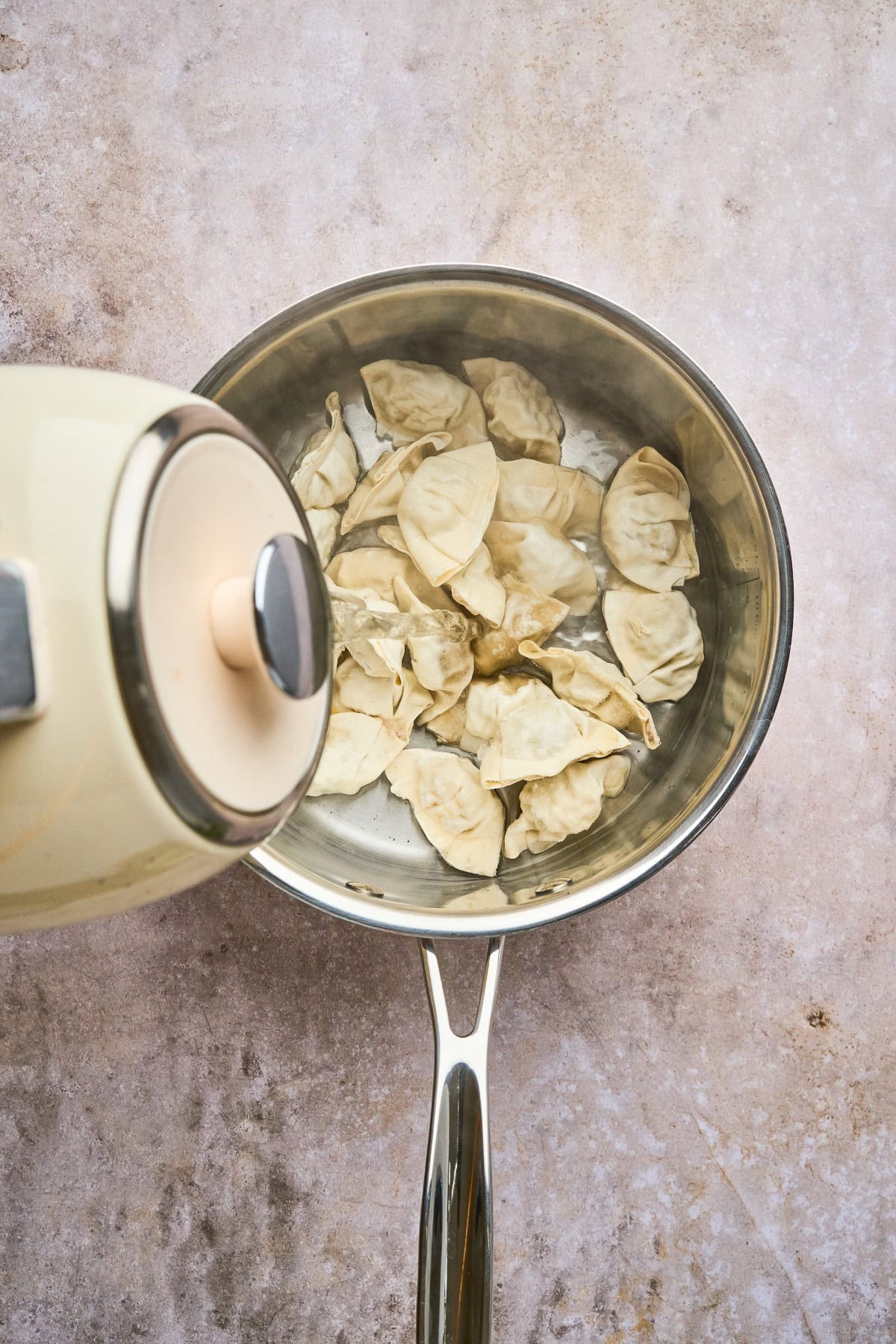 Adding water to boil the wontons. 