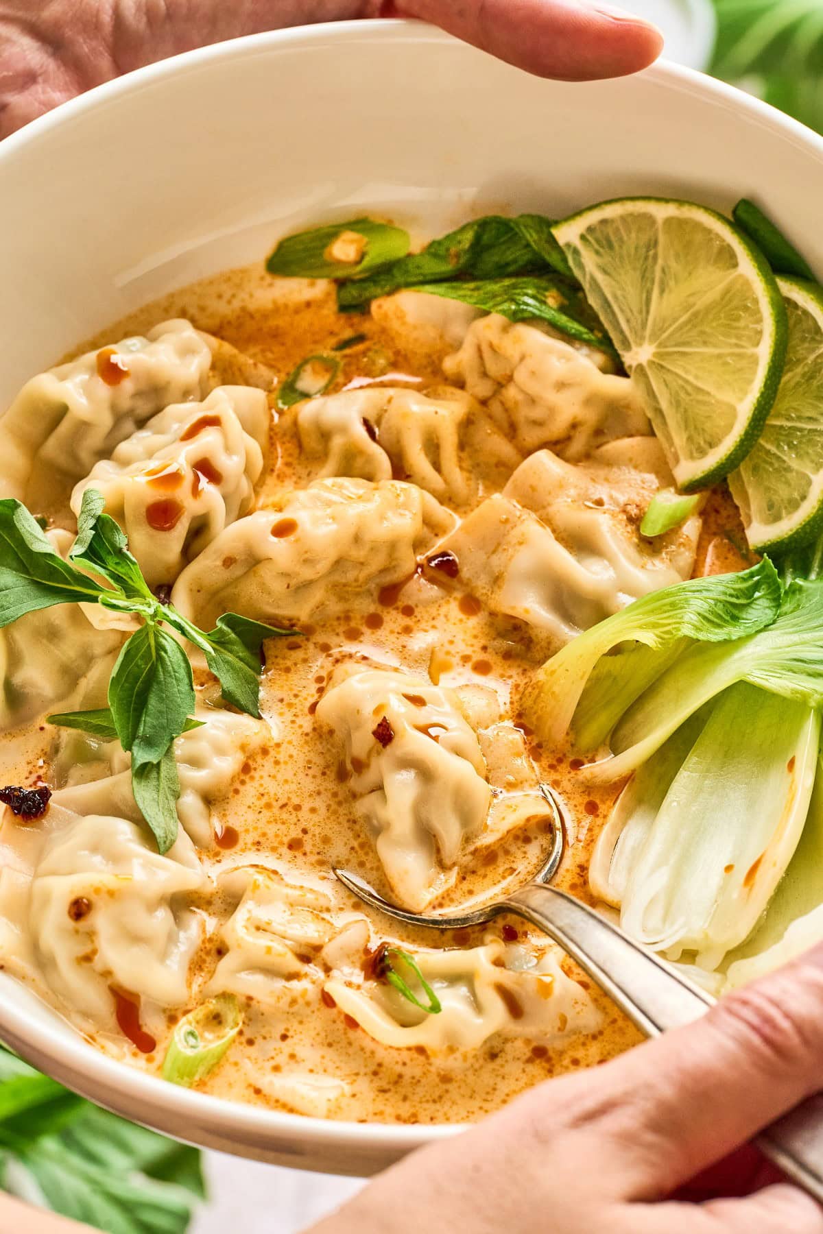 Holding a bowl of Coconut Curry Soup with Wontons. 