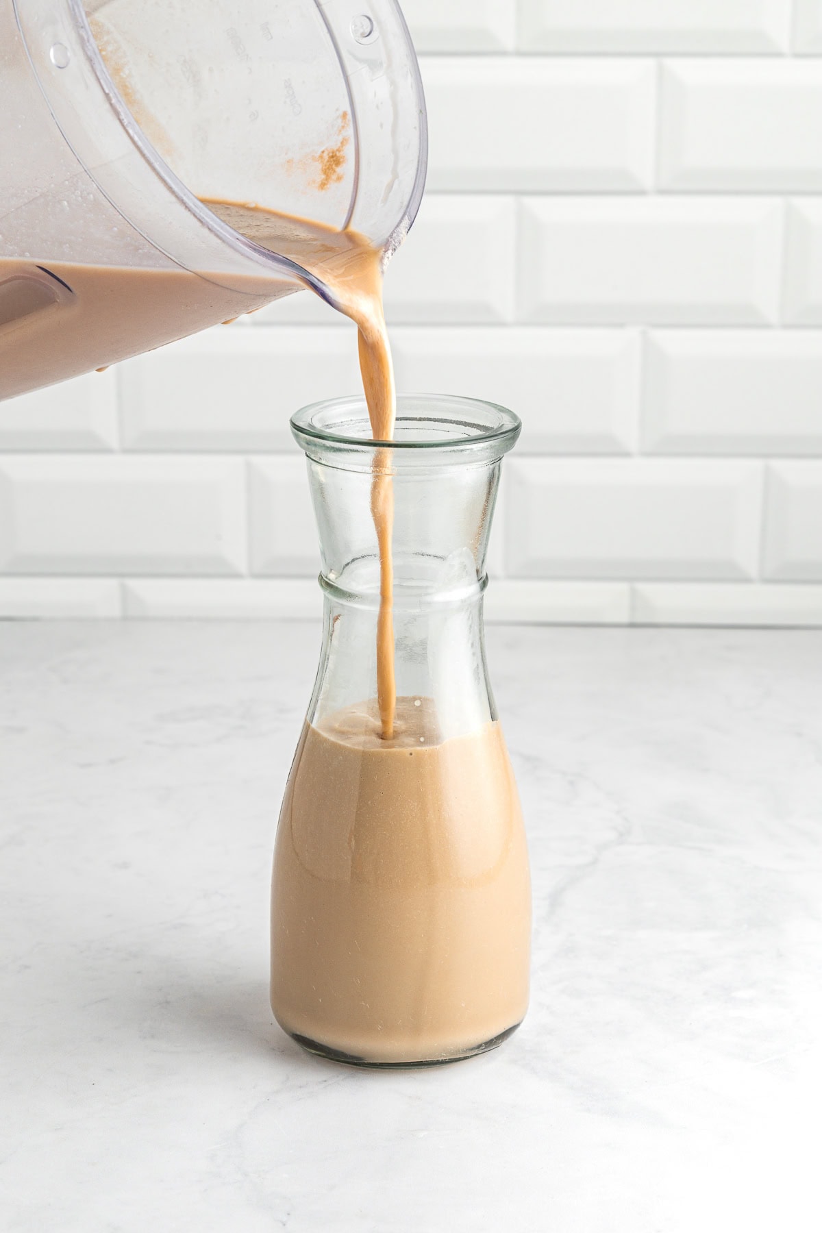 Pouring Baileys into a glass bottle.