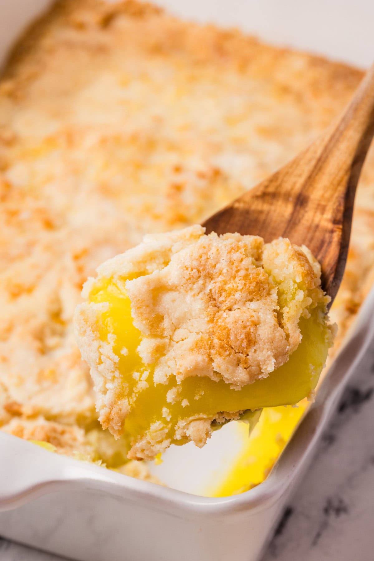 Need a quick and easy recipe? This Lemon Dump Cake is not only easy but delicious. It transports well, making a great potluck offering, and is summery and bright. Lemon lovers will be thrilled. Taking a spoonful of Lemon Dumb Cake.