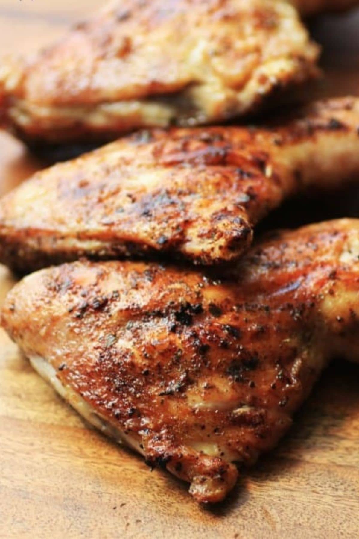 Pieces of brick chicken on a wooden cutting board.