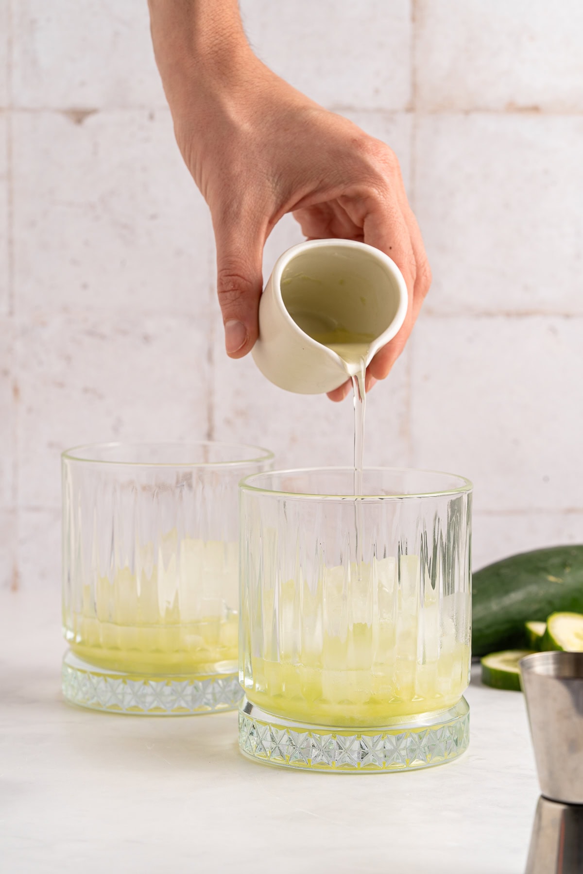 Vodka Cucumber Cocktail is the perfect summer porch sipper on a hot day!! It is easy enough to make for yourself, but perfect for any gathering or BBQ! Your company will rave over it. Pouring melon syrup.