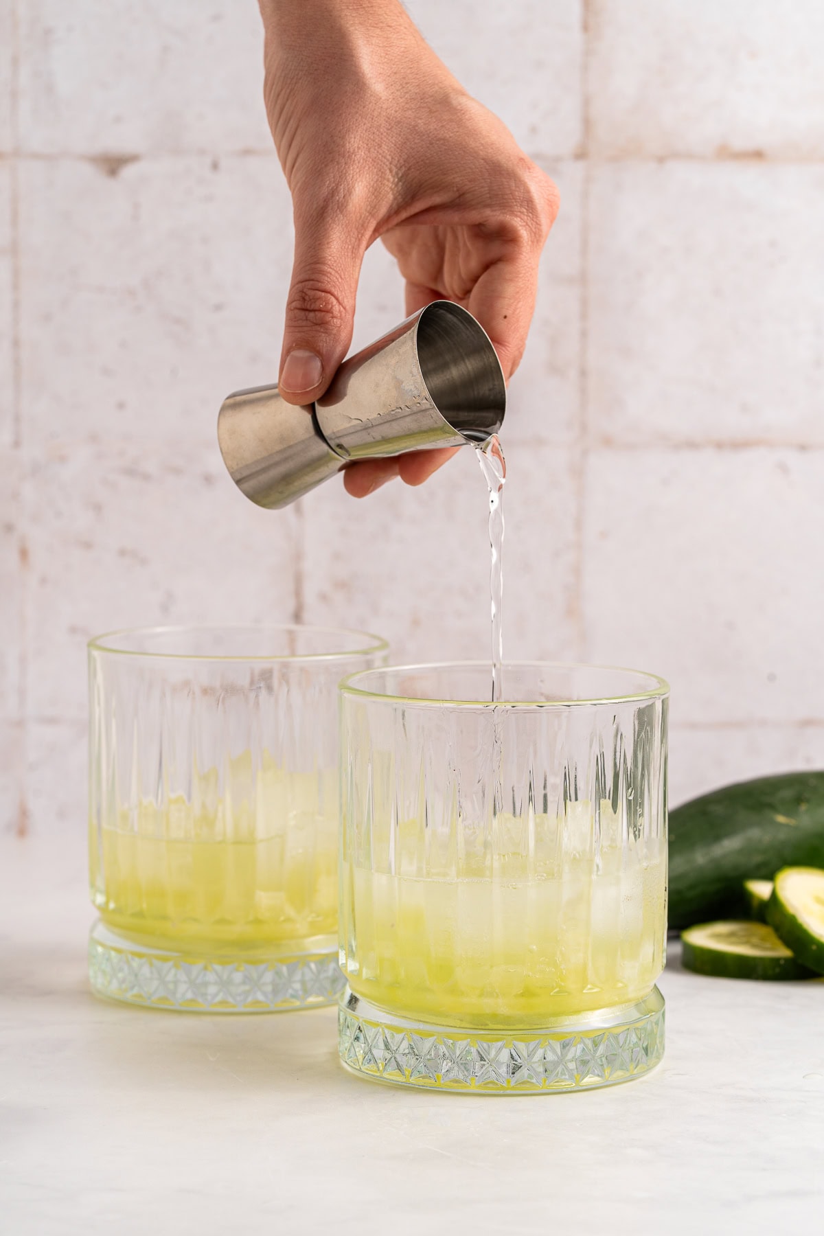 Vodka Cucumber Cocktail is the perfect summer porch sipper on a hot day!! It is easy enough to make for yourself, but perfect for any gathering or BBQ! Your company will rave over it. Pouring vodka.