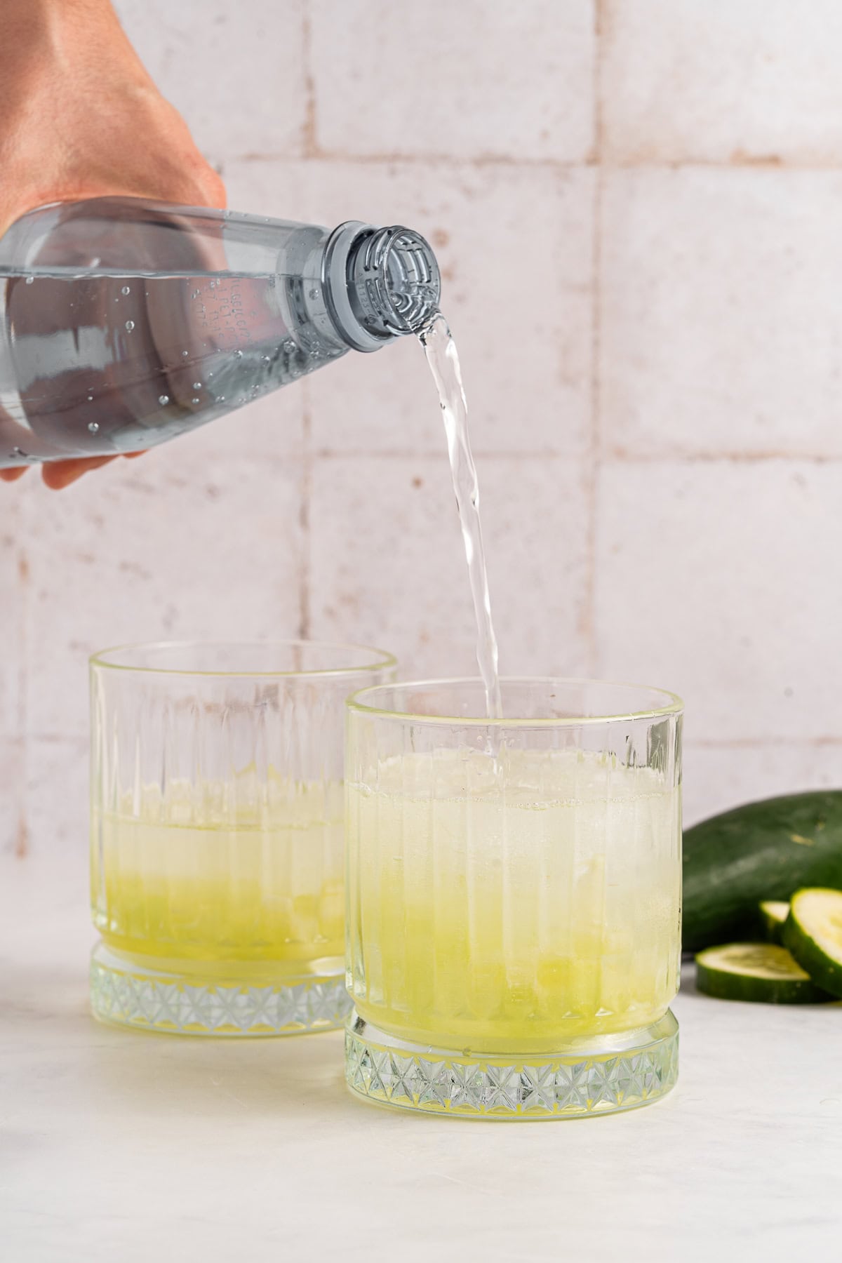 Vodka Cucumber Cocktail is the perfect summer porch sipper on a hot day!! It is easy enough to make for yourself, but perfect for any gathering or BBQ! Your company will rave over it. Pouring club soda.