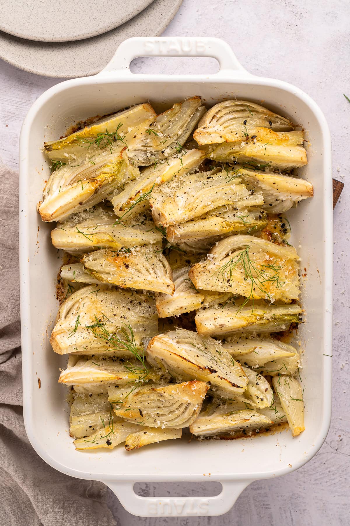 This recipe for Baked Fennel With Parmesan Cheese is unique and delicious. Baking fennel makes it mellow, and the butter and cheese make it excellent. Baked Fennel in a baking dish.