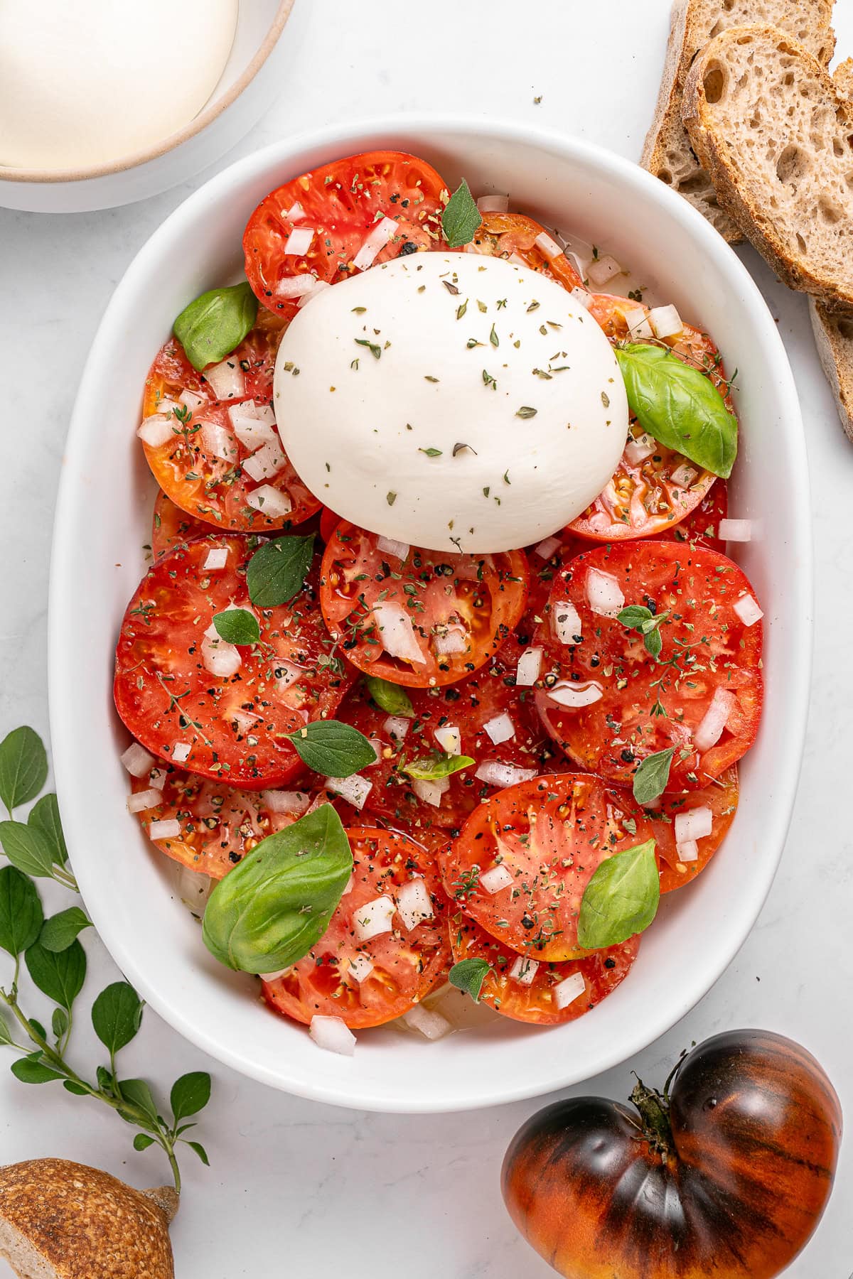 A Tomato Burrata Salad like this can be a show-stopper for any get-together. Use fresh heirloom tomatoes if available. They are the best with the creamy burrata. Burrata cheese over sliced tomatoes.