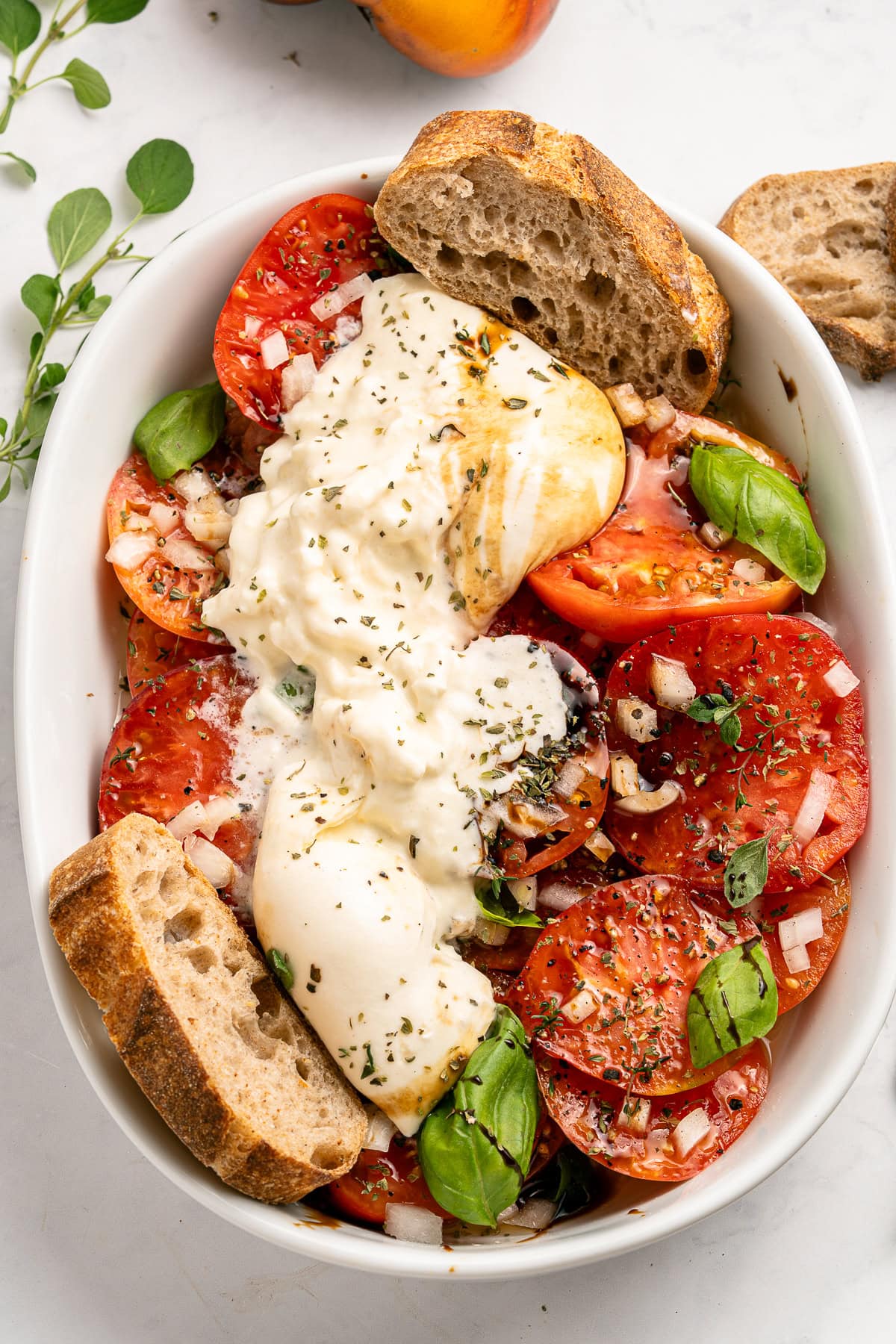 A Tomato Burrata Salad like this can be a show-stopper for any get-together. Use fresh heirloom tomatoes if available. They are the best with the creamy burrata. Tomato and burrata salad with bread.