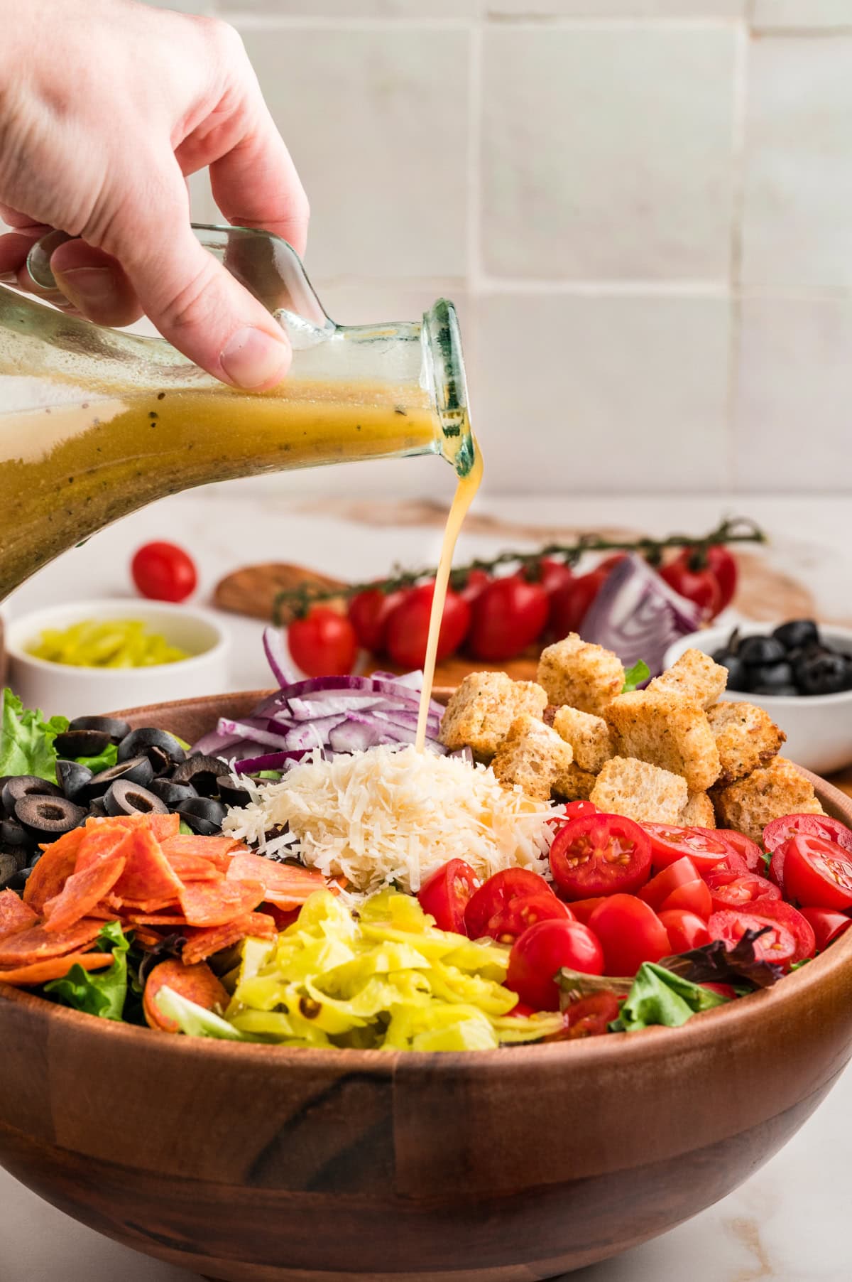 An Italian Chopped Salad adds a lot of bold flavor to any meal, but also it is healthy and delicious. This salad goes with so many mains you will want to make it again and again. Pouring dressing on salad.