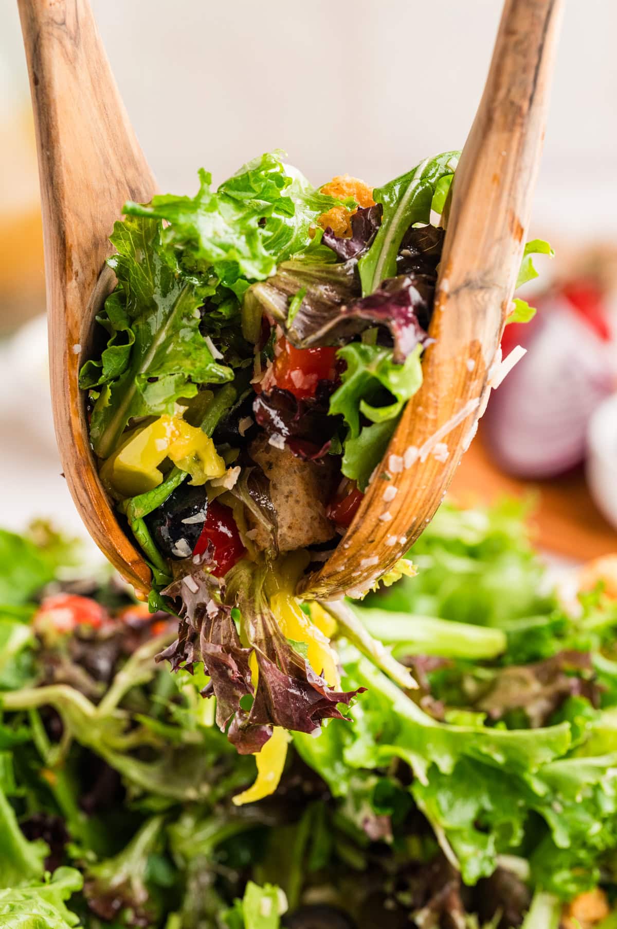 An Italian Chopped Salad adds a lot of bold flavor to any meal, but also it is healthy and delicious. This salad goes with so many mains you will want to make it again and again. Grabbing salad from a bowl with servers.
