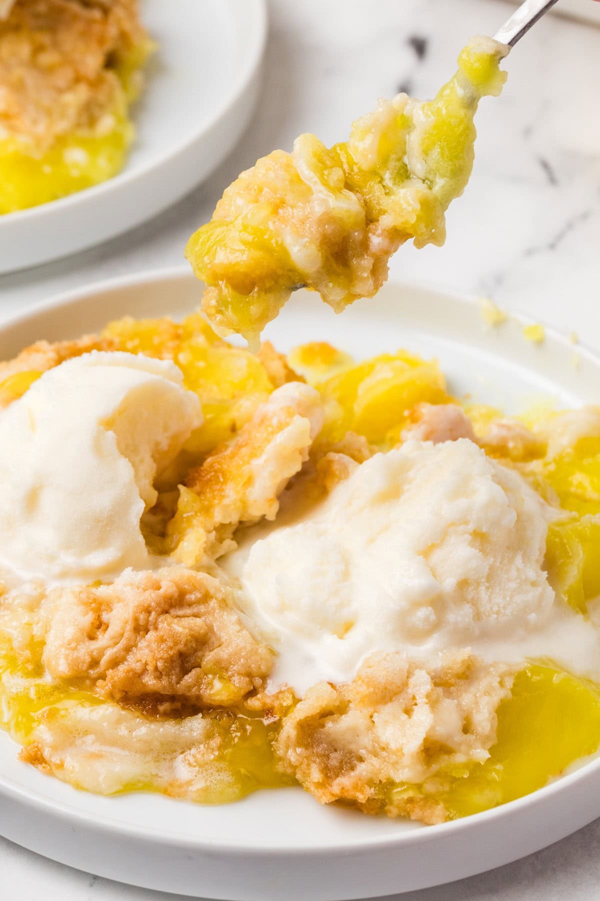 Need a quick and easy recipe? This Lemon Dump Cake is not only easy but delicious. It transports well, making a great potluck offering, and is summery and bright. Lemon lovers will be thrilled. Taking a forkful of cake.