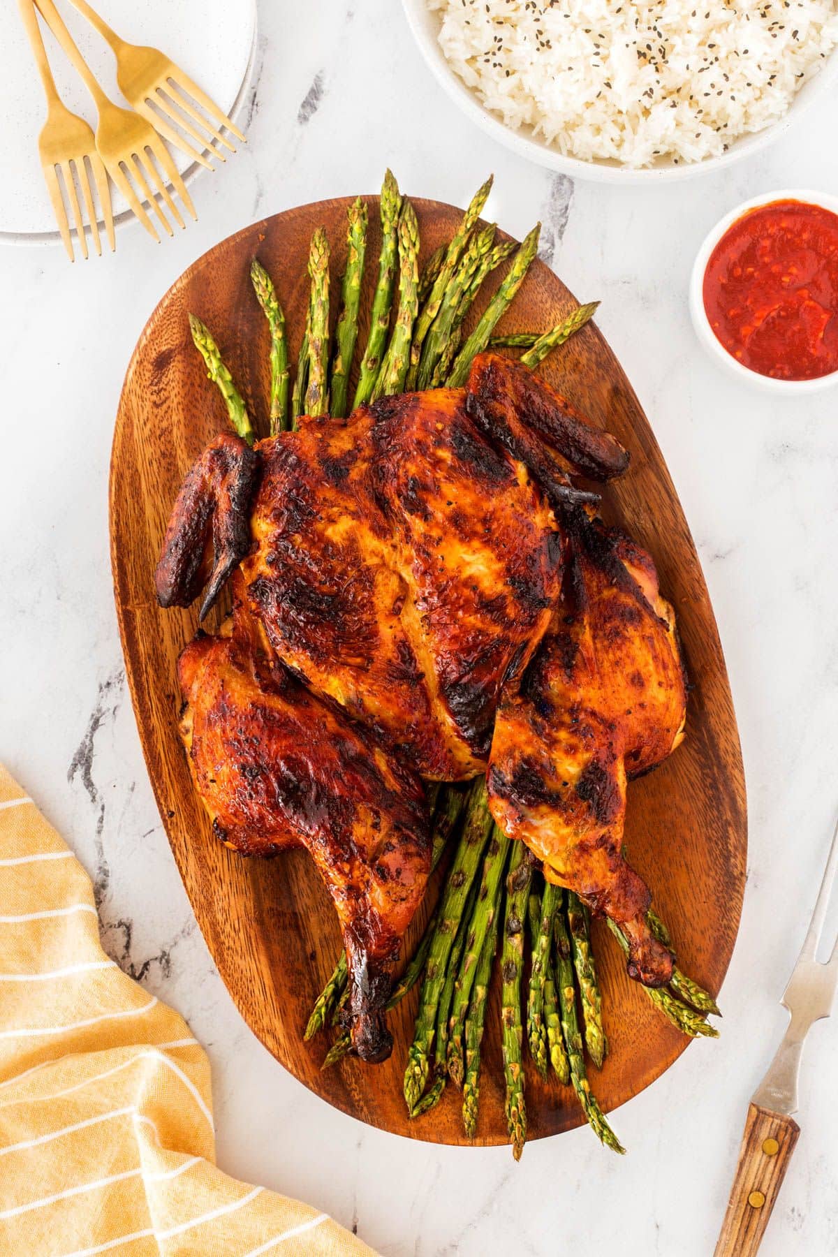 Spatchcock chicken on a serving platter with asparagus.