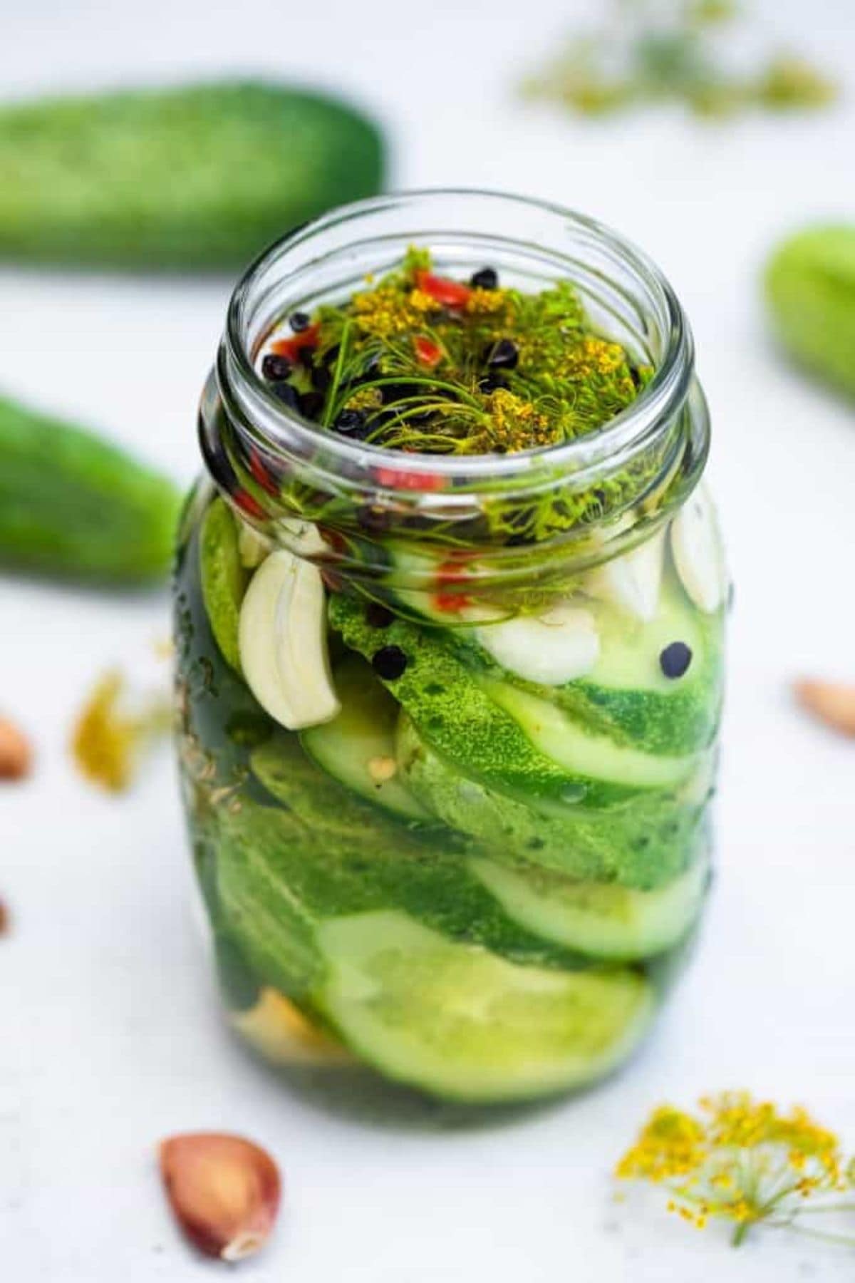 Cucumbers and herbs in large jar.