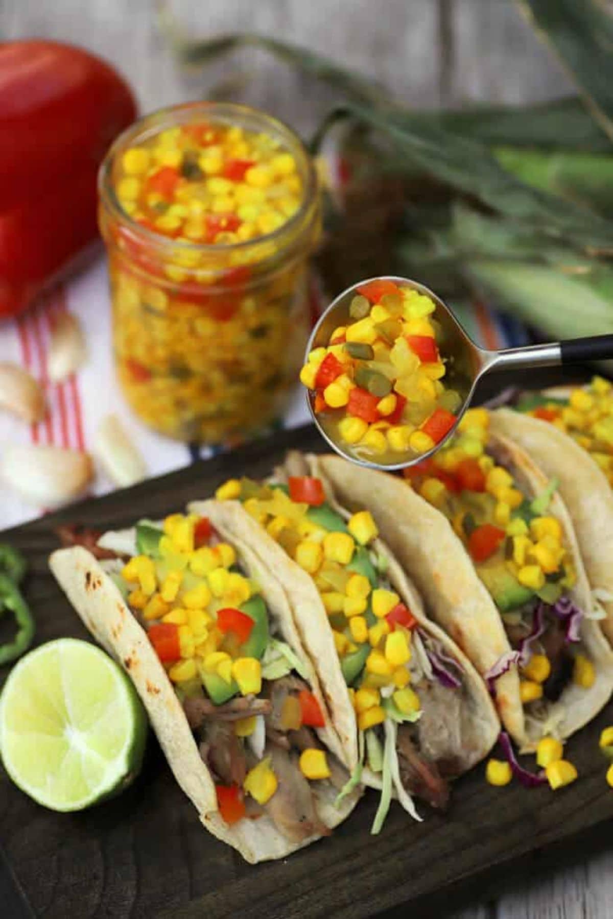 Corn salsa being spread on top of tacos.