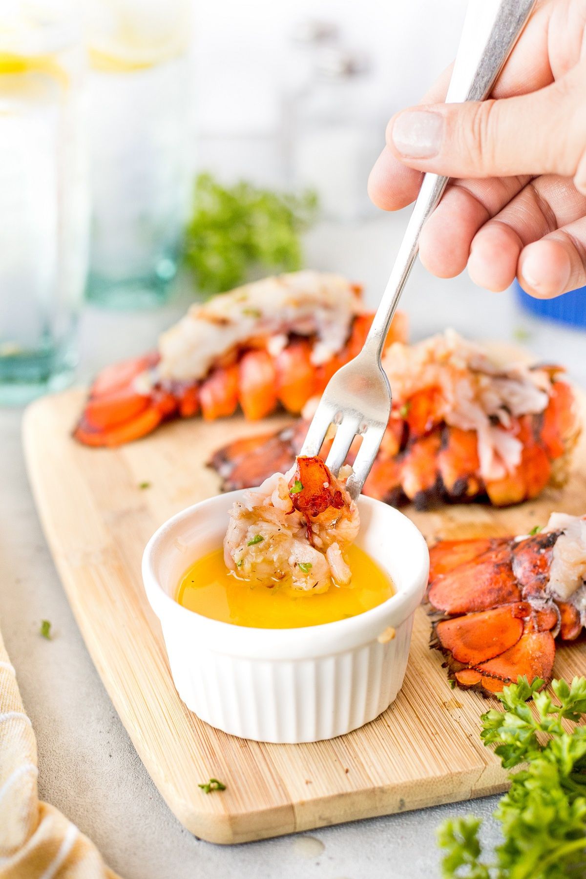 Piece of lobster tail being dipped in butter.