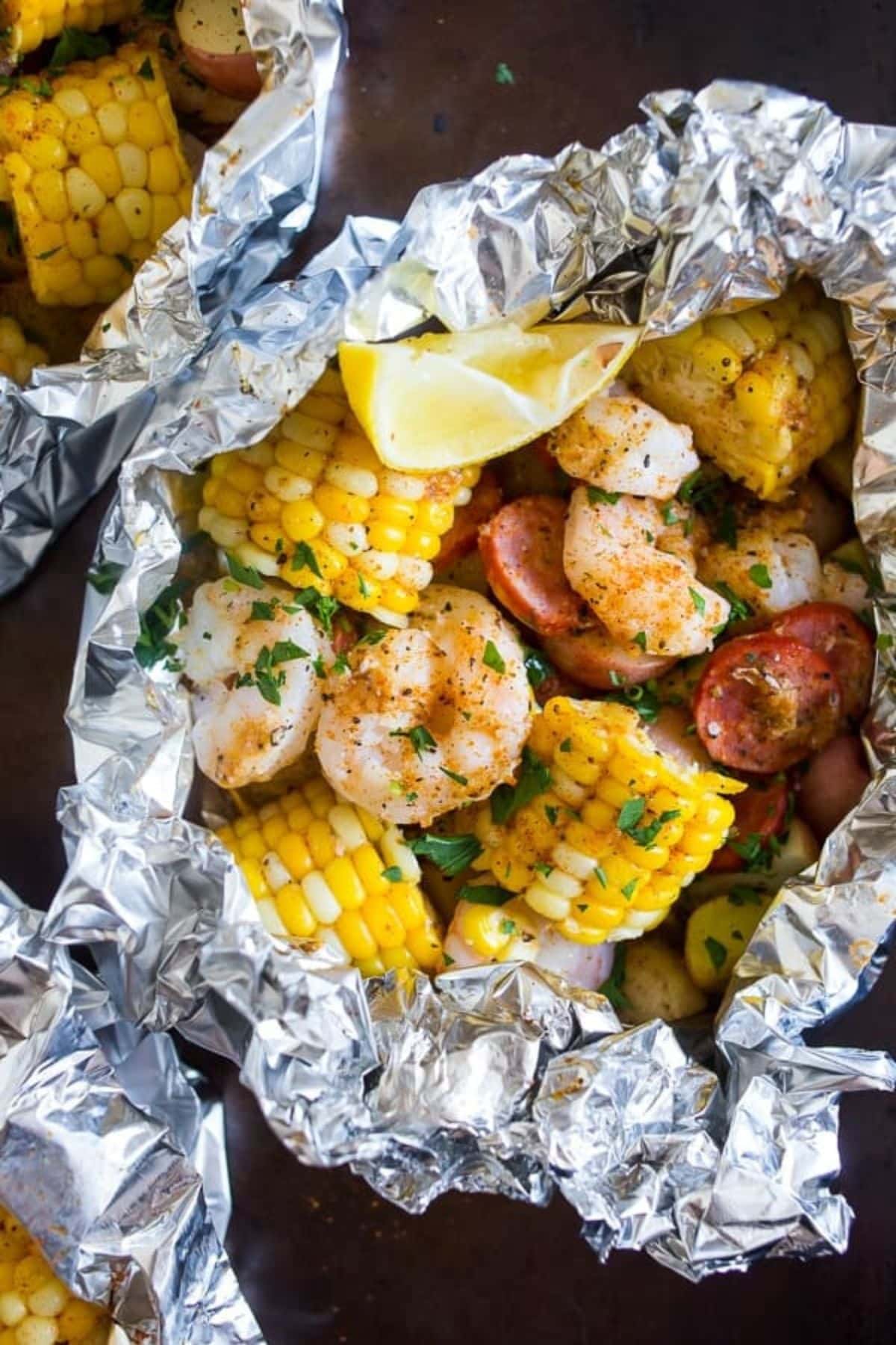 Are you enjoying the great outdoors this summer and wondering what to eat? Try some of these 20 Awesome Campfire Recipes!! Shrimp and corn in foil.
