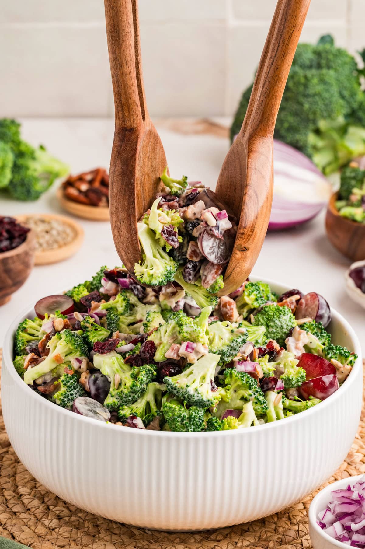 This Broccoli Salad is a keeper that you will want to bring out on a constant rotation. It is perfect for a summer BBQ, picnic or really at any time of the year. Picking up salad with tongs.