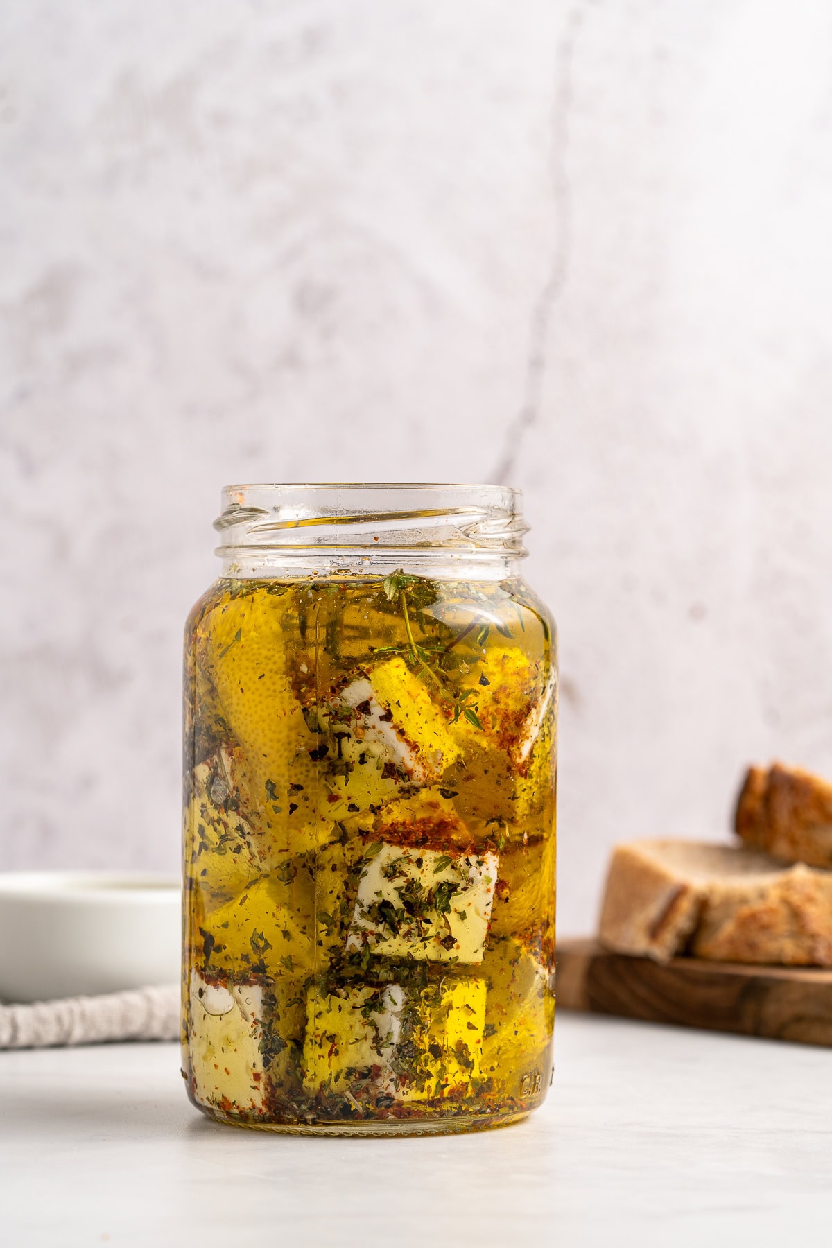 Marinated Feta is a great appetizer on its own or added to a charcuterie or Mediterranean platter. It is also amazing with a summer salad or Greek salad. Covering cheese with olive oil.