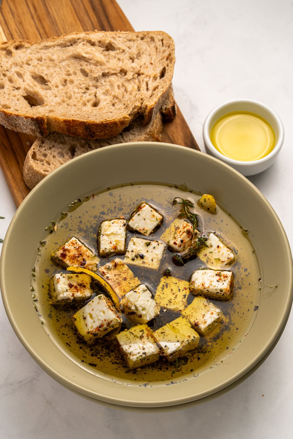 Marinated Feta is a great appetizer on its own or added to a charcuterie or Mediterranean platter. It is also amazing with a summer salad or Greek salad. Marinated feta served with crusty bread.