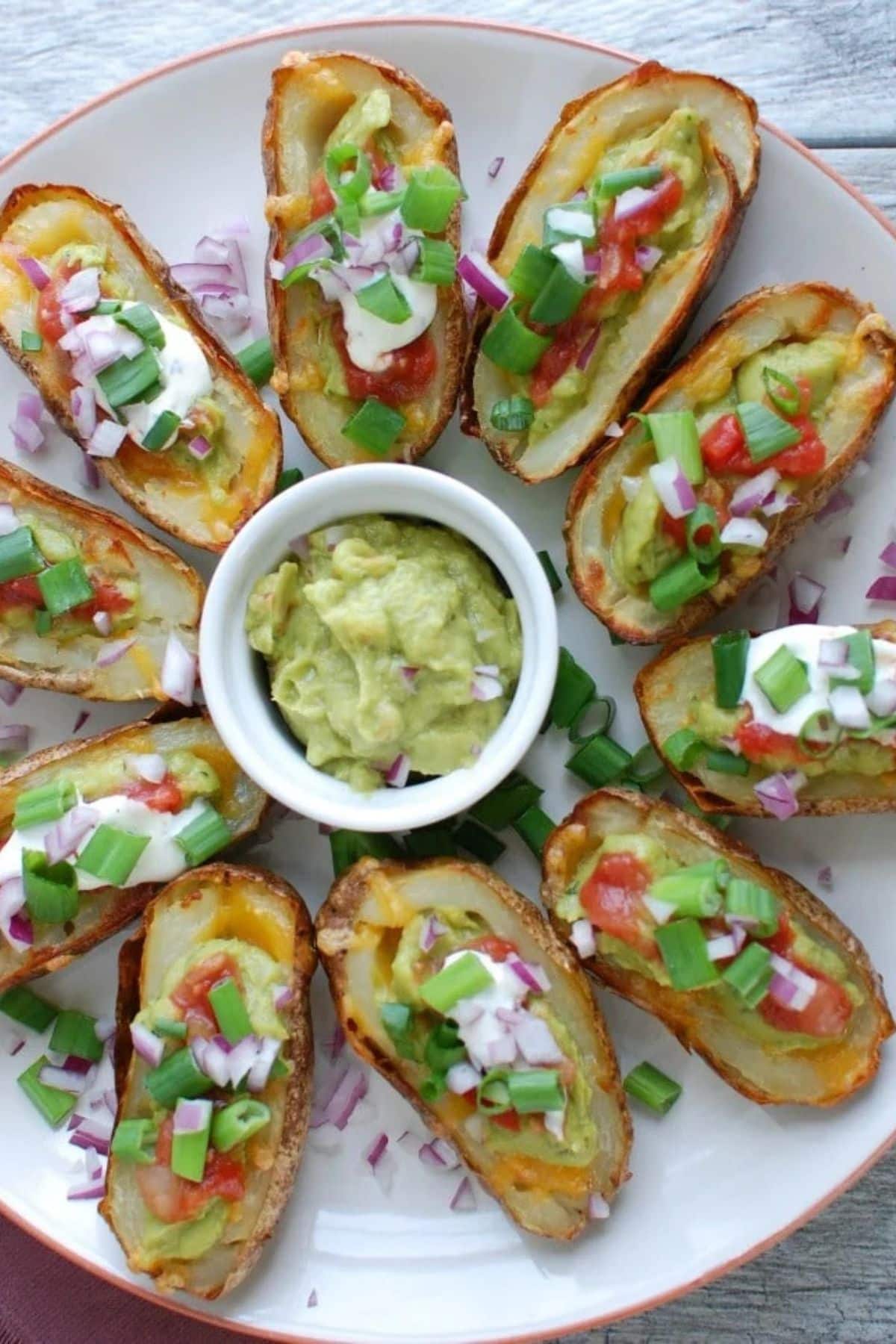 Potatoes topped with guacamole on plate.