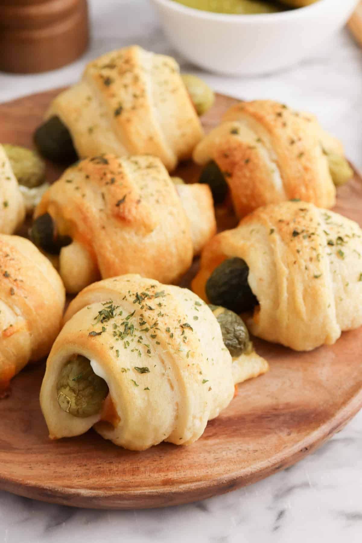 Pickles in a blanket on a cutting board.