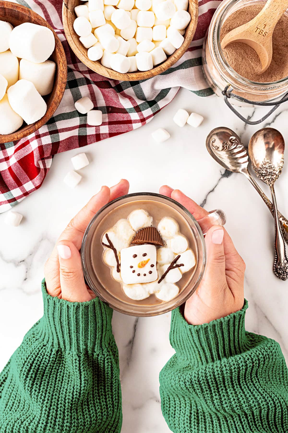 Holding a cup of cocoa with the marshmallow floating in. 