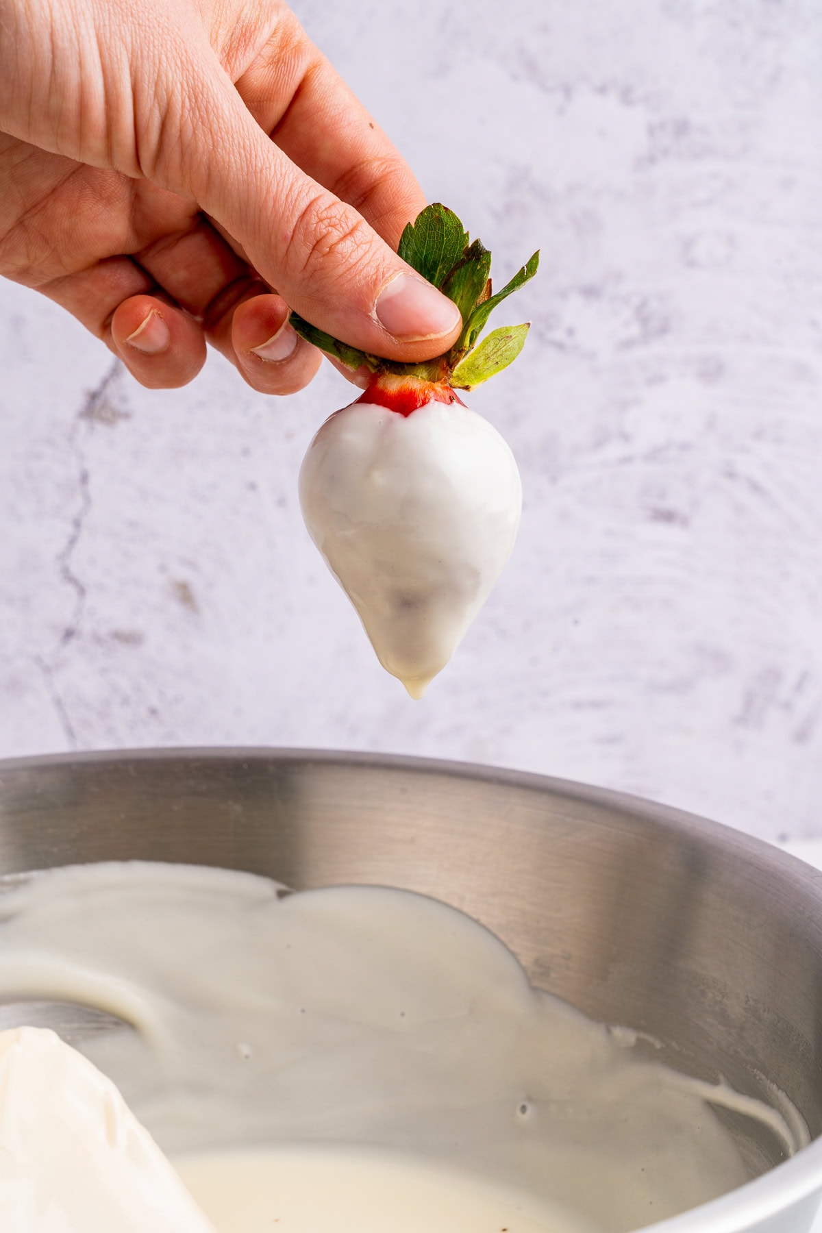 Dipping strawberries in melted white chocolate.