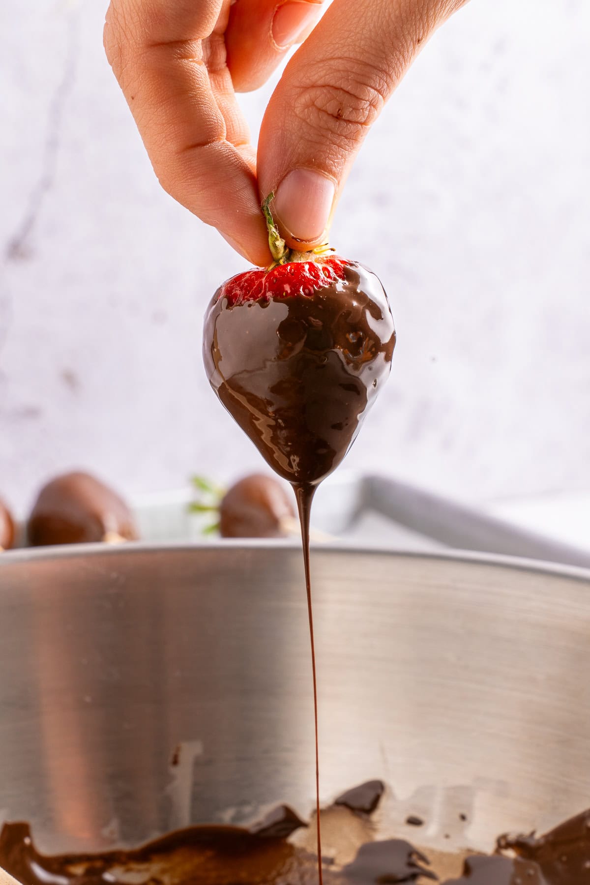 Dipping strawberries in melted chocolate.