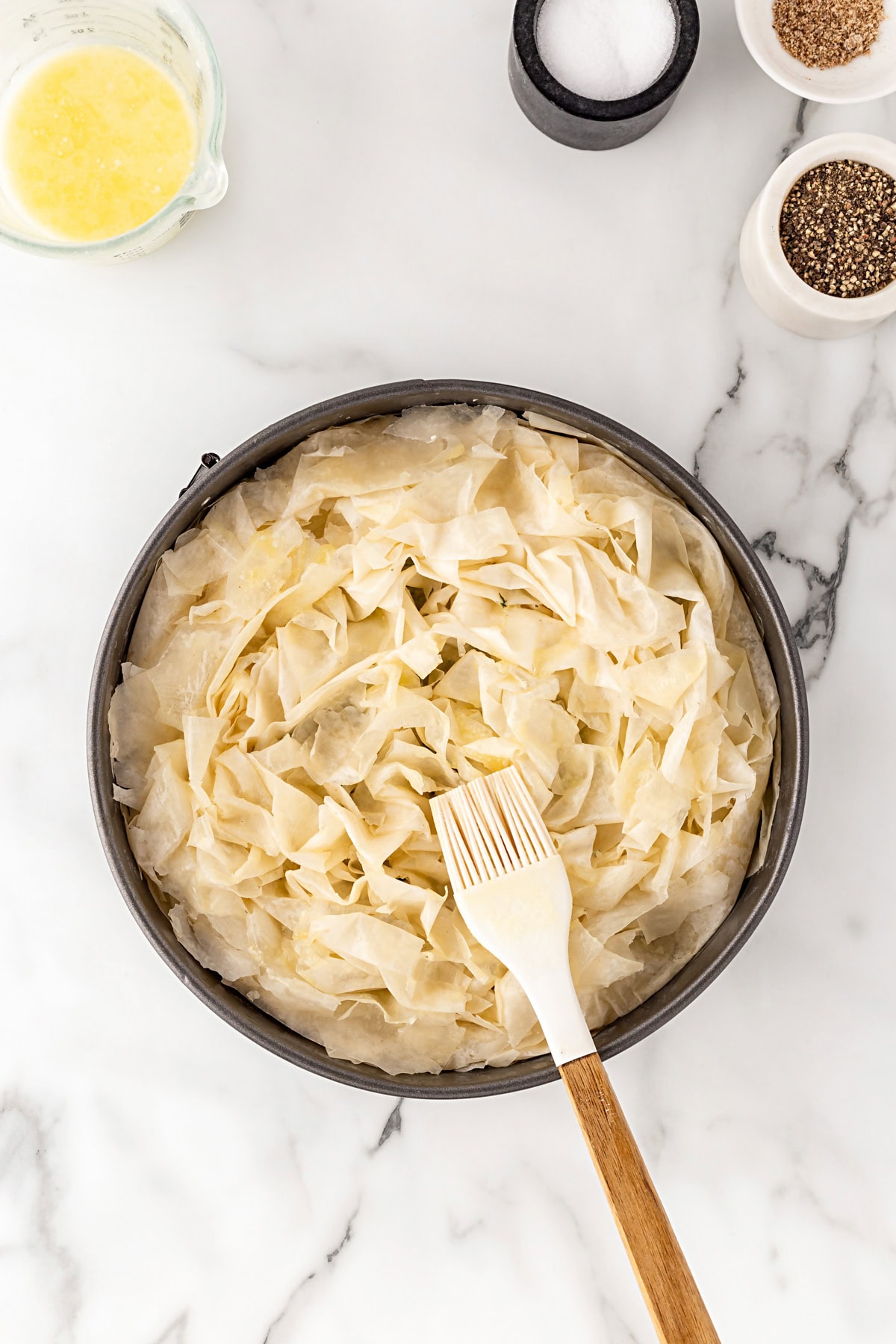 Brushing top of the pie with butter. 