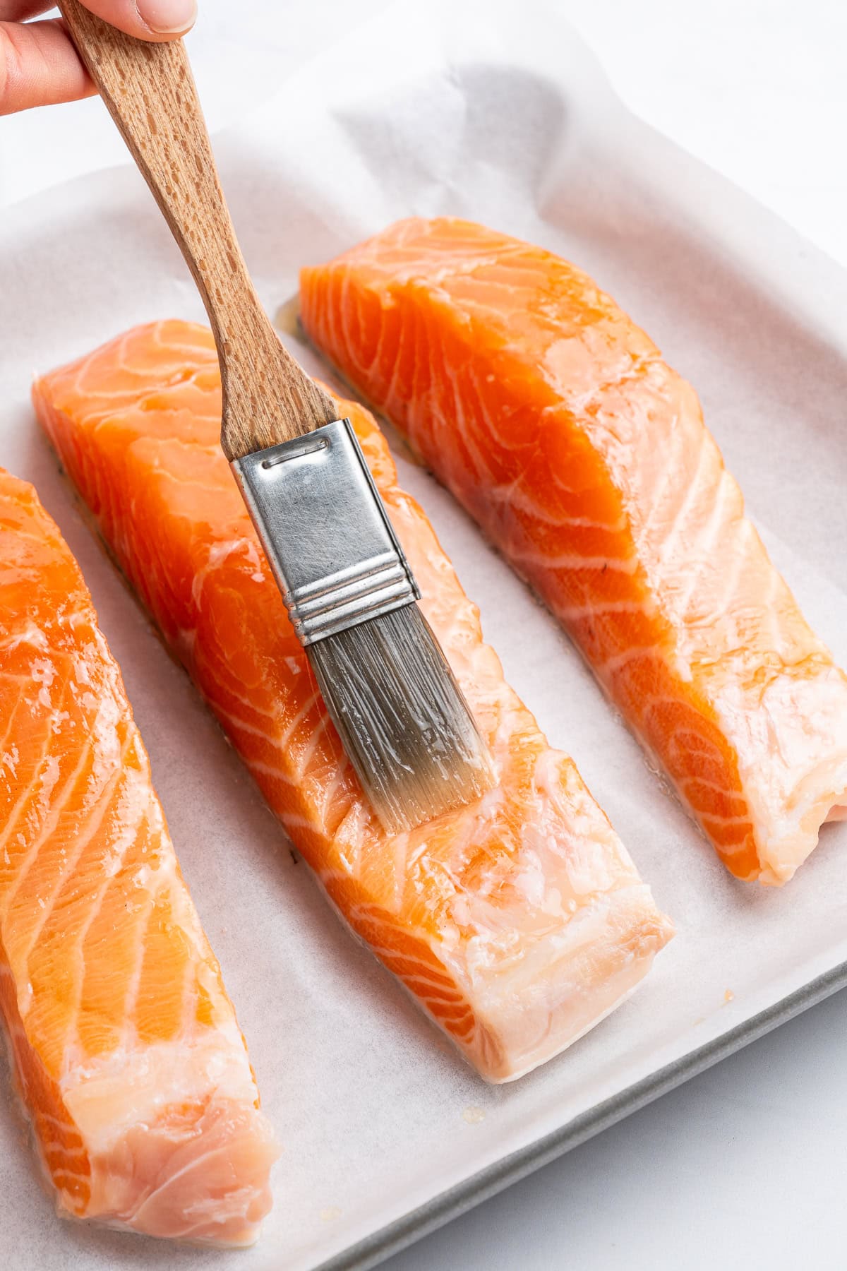 Brushing olive oil over salmon.