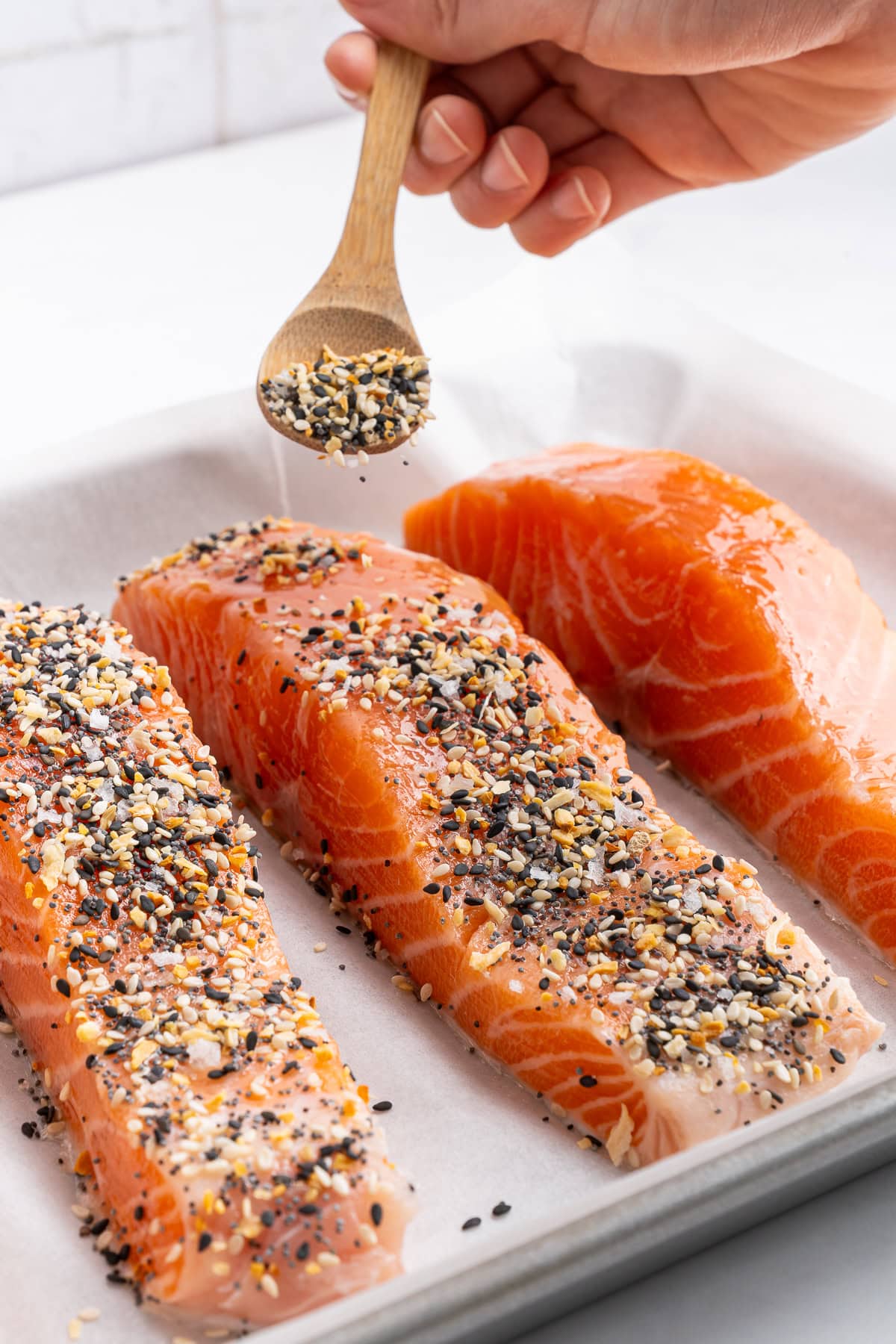 Coating salmon with everything bagel seasoning.