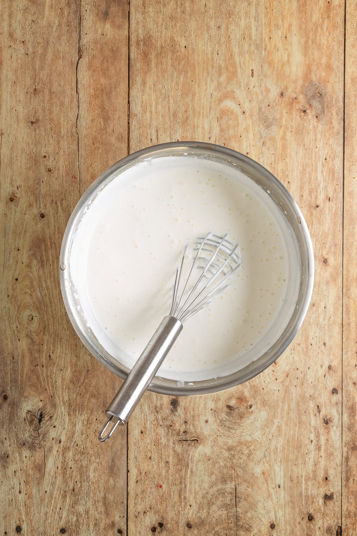 Heavy cream in a bowl with a whisk. 
