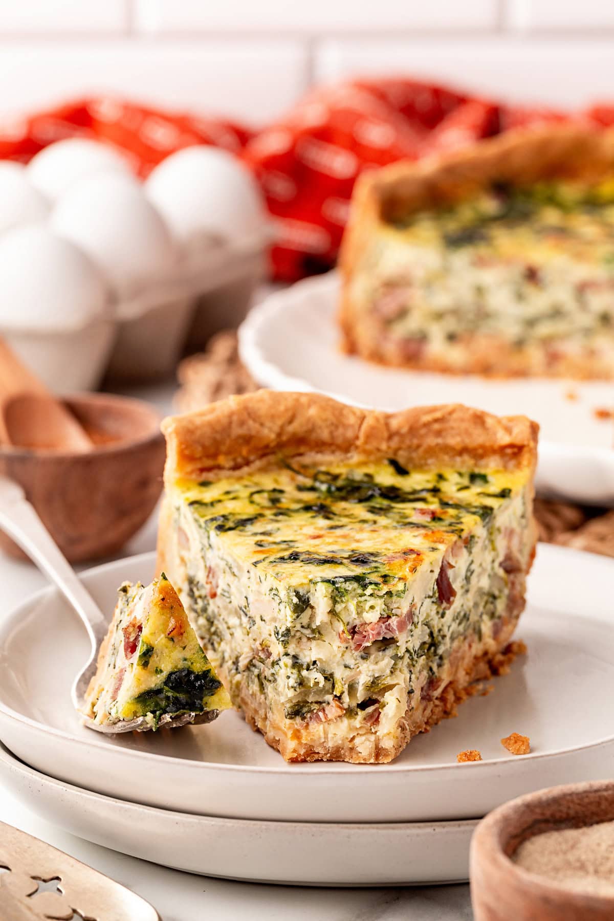 Taking a forkful of the deep dish quiche on a plate. 