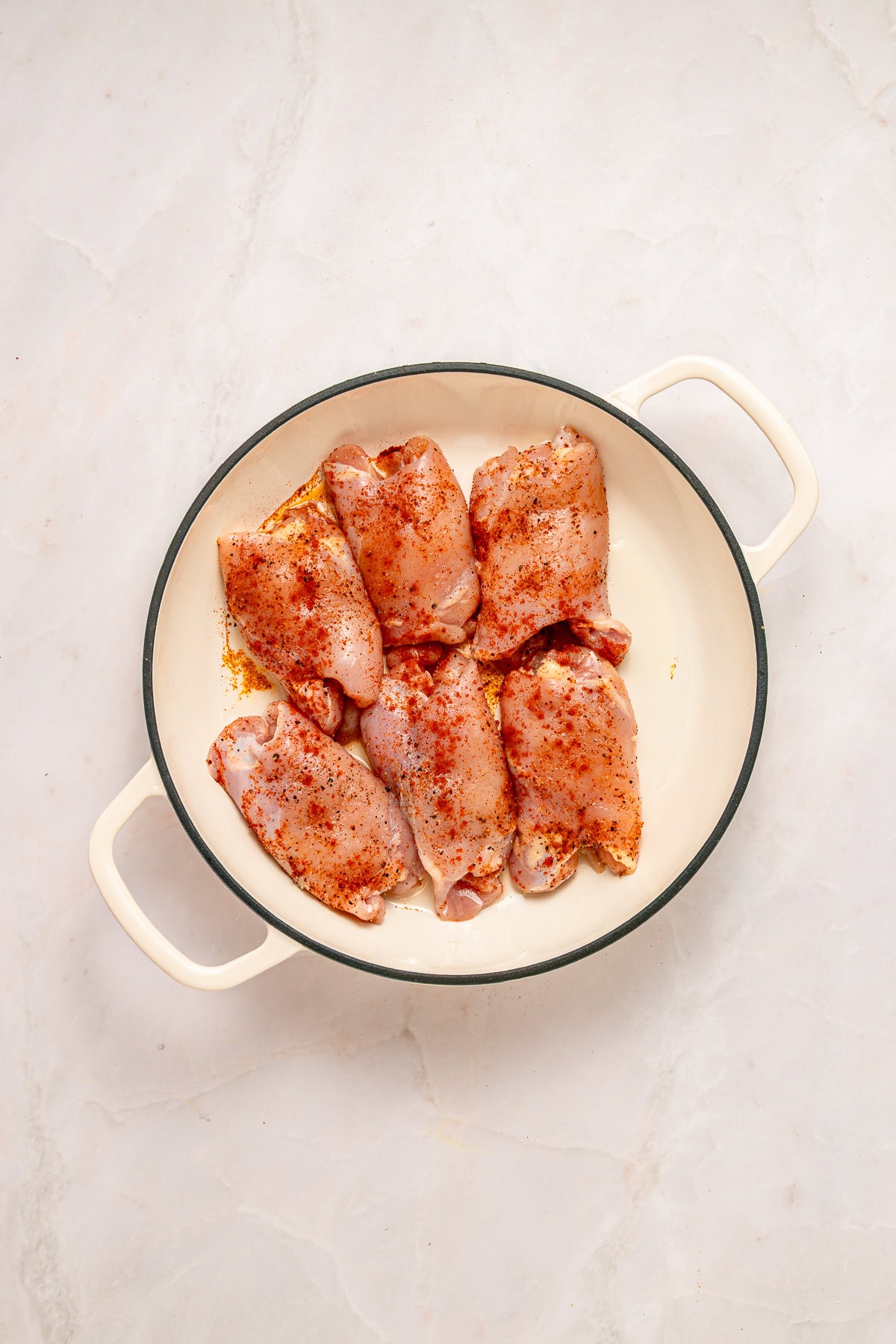 Searing chicken thighs in a skillet.