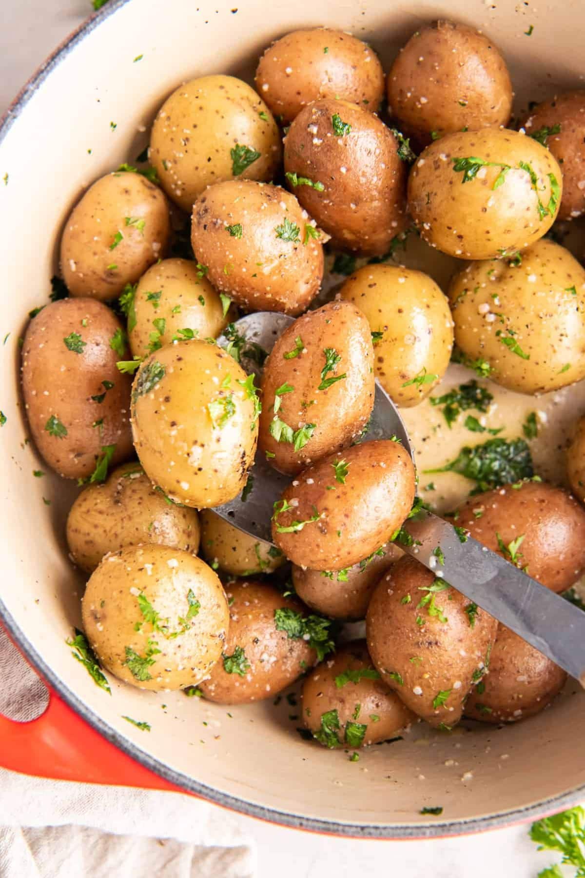 Baby potatoes coated in parsley in pot.