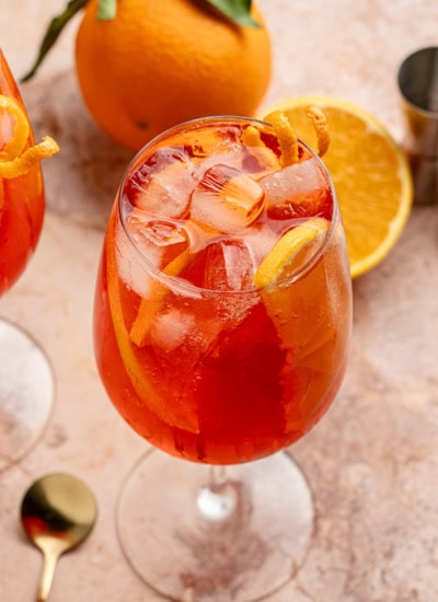Cocktail with oranges in the background.