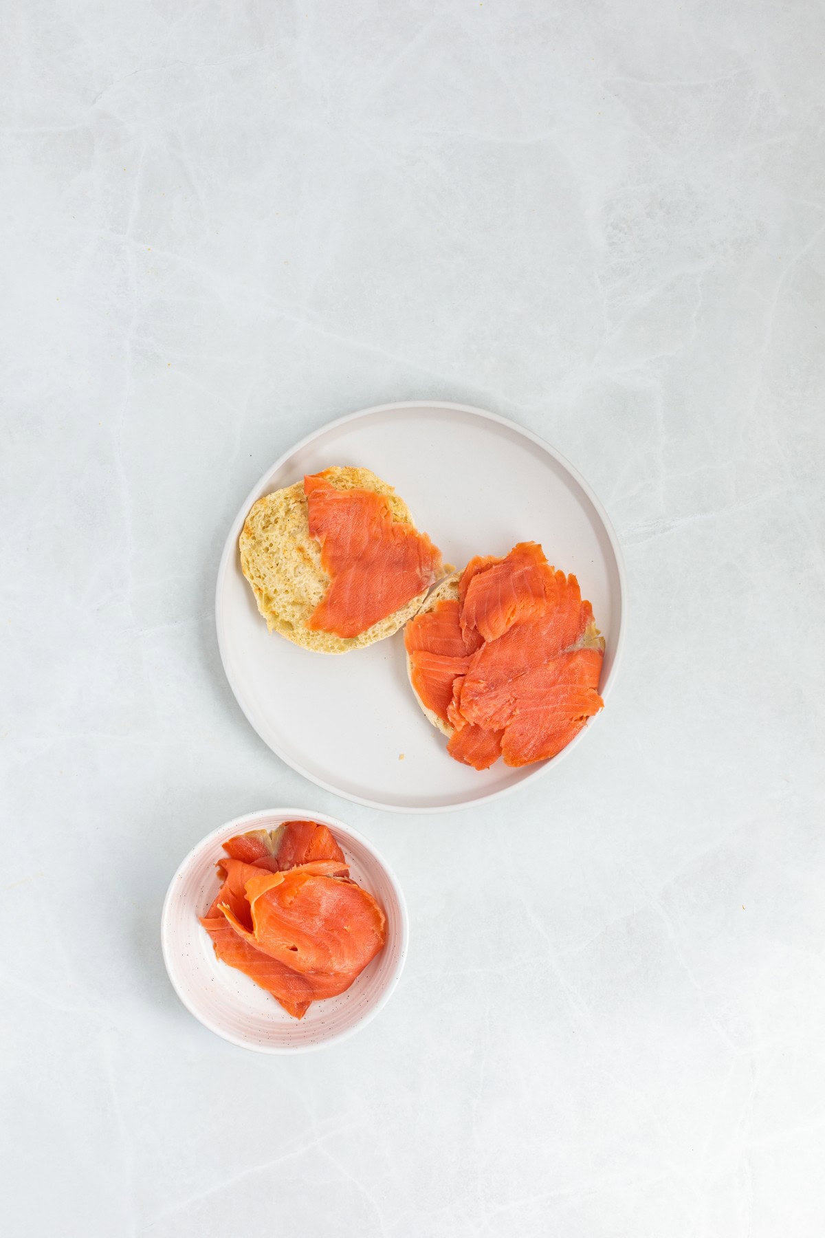 Adding smoked salmon to an English muffin. 
