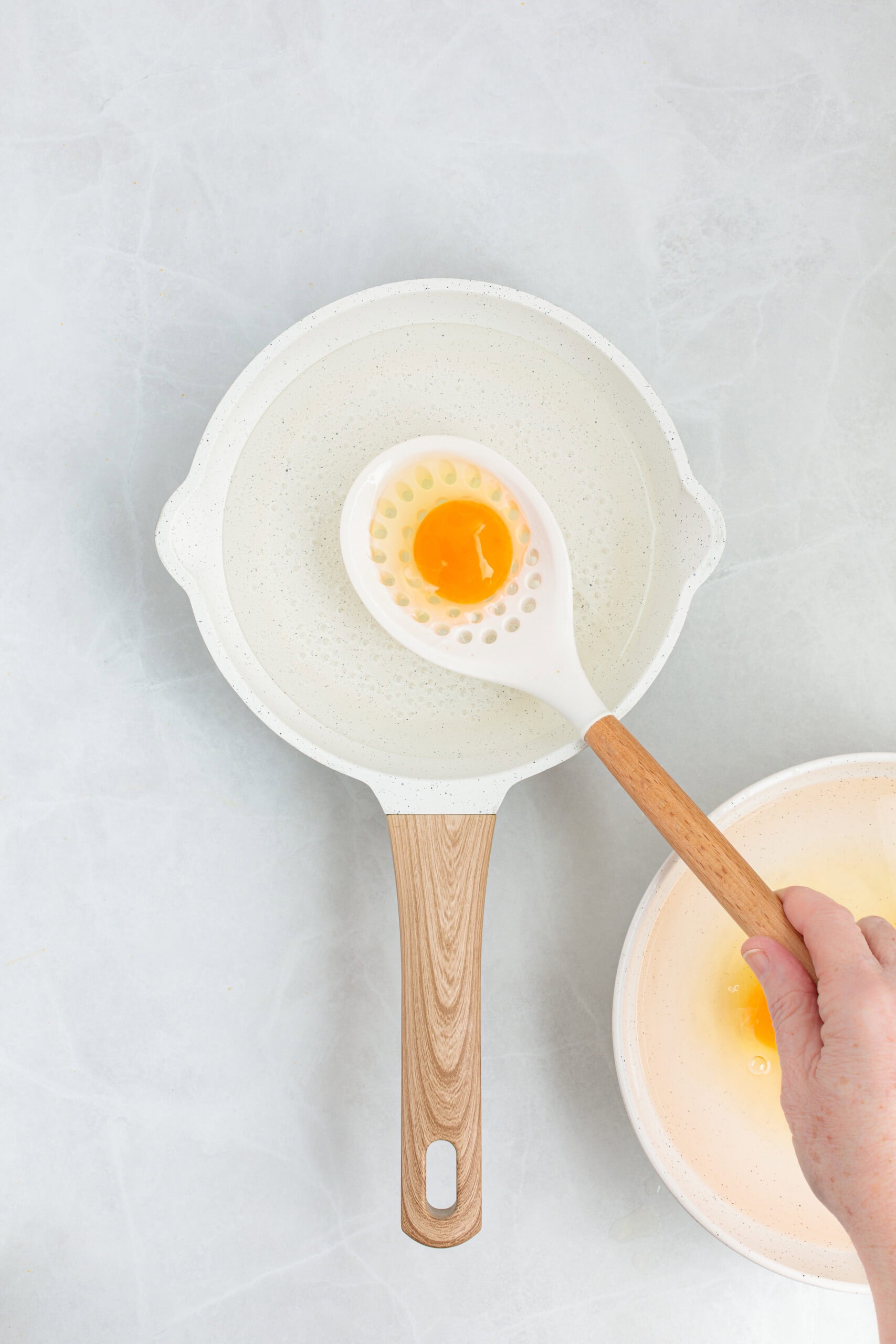 Adding egg to simmering water. 