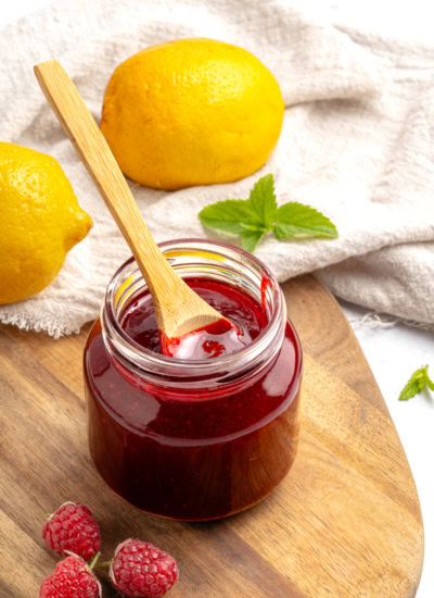 Wooden spoon in a jar of raspberry coulis.