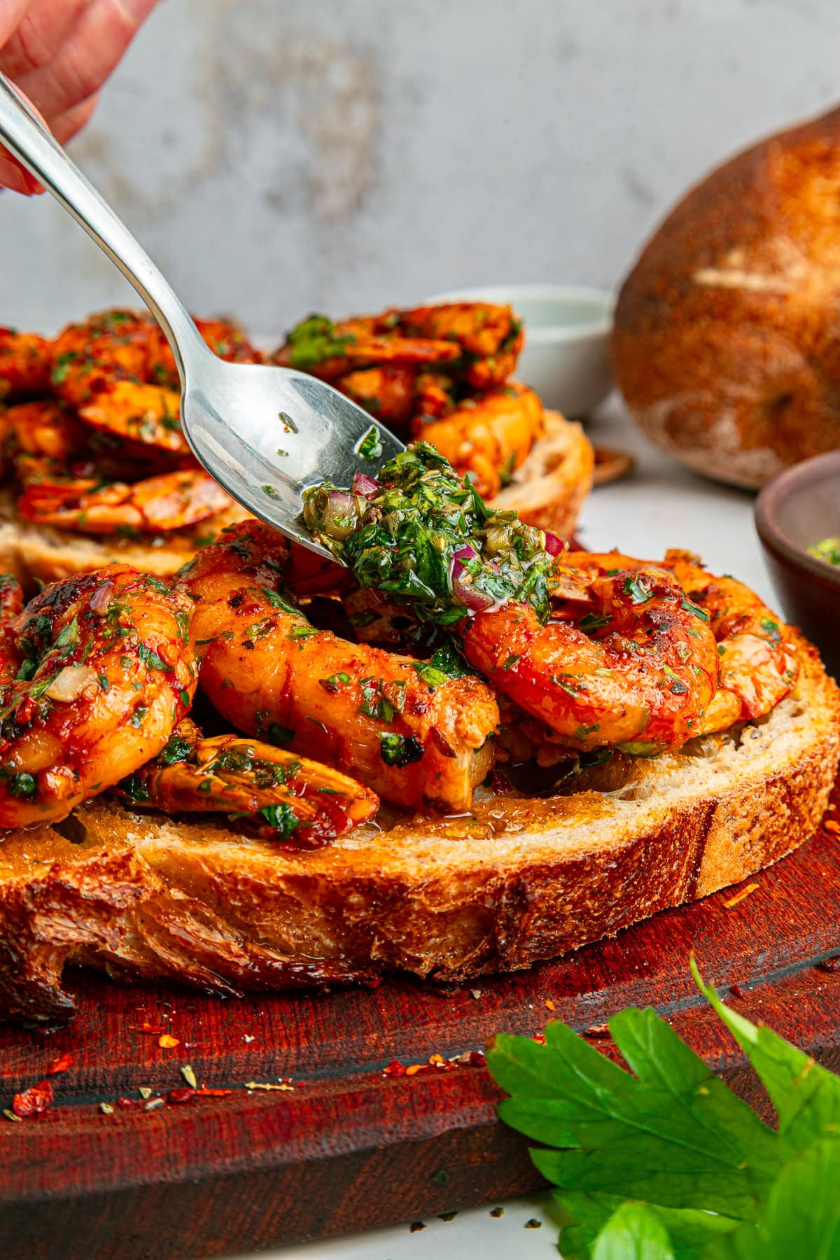 Spooning chimichurri over shrimp.