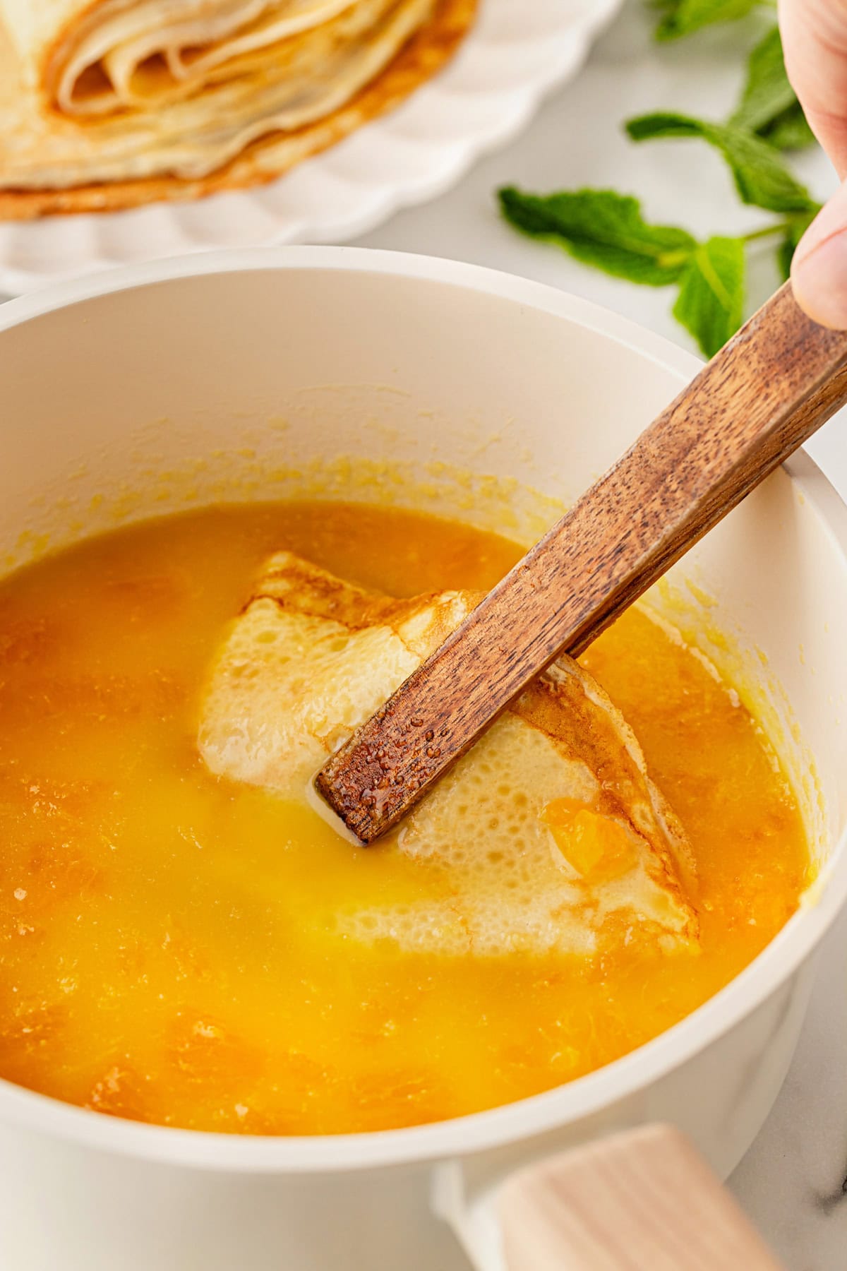 Dipping crepes in sauce.