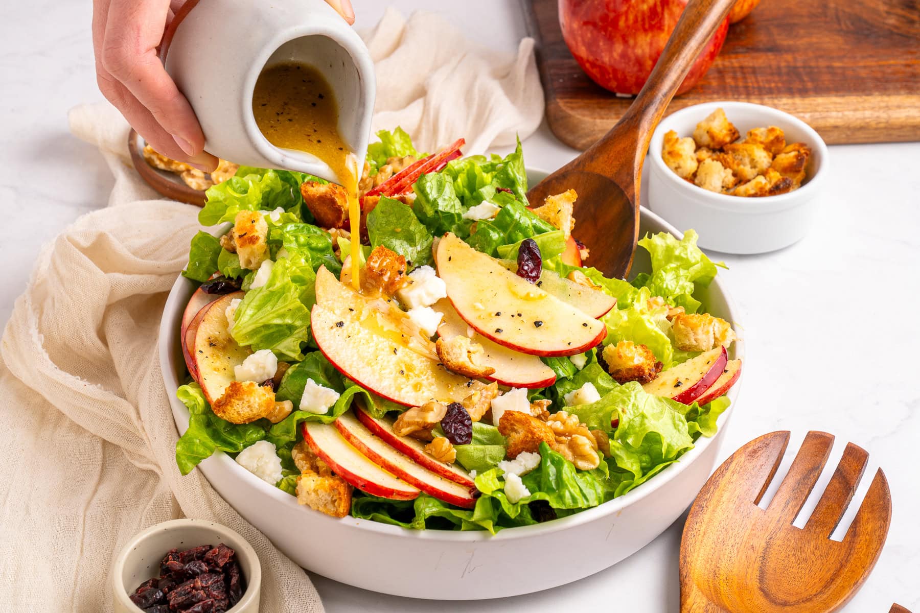 Pouring salad dressing over the salad.
